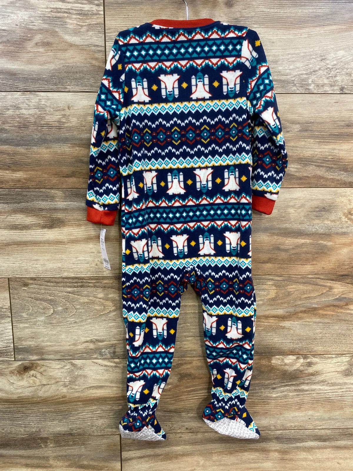 Back view of navy rocket ship blanket sleeper size 3T showing southwestern pattern, footed legs, and red cuffs on wooden floor