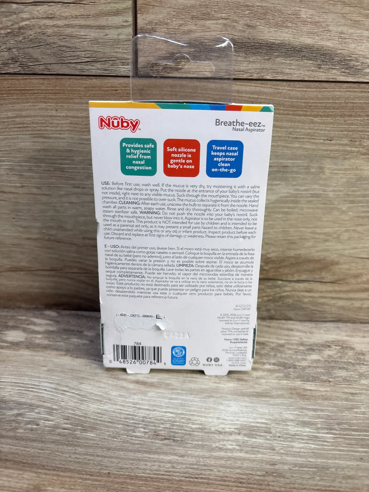 Back view of Nuby Breathe-EEZ Nasal Aspirator showcasing soft silicone nozzle and travel case on wood-grain background