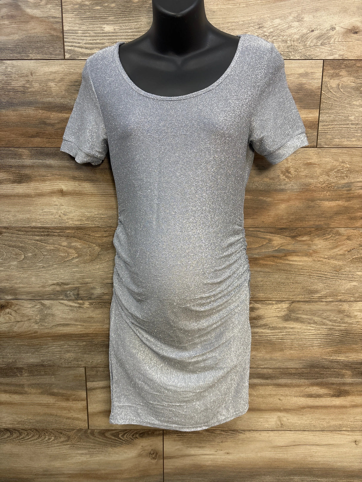 Silver shimmer maternity dress with short sleeves on mannequin against wood background