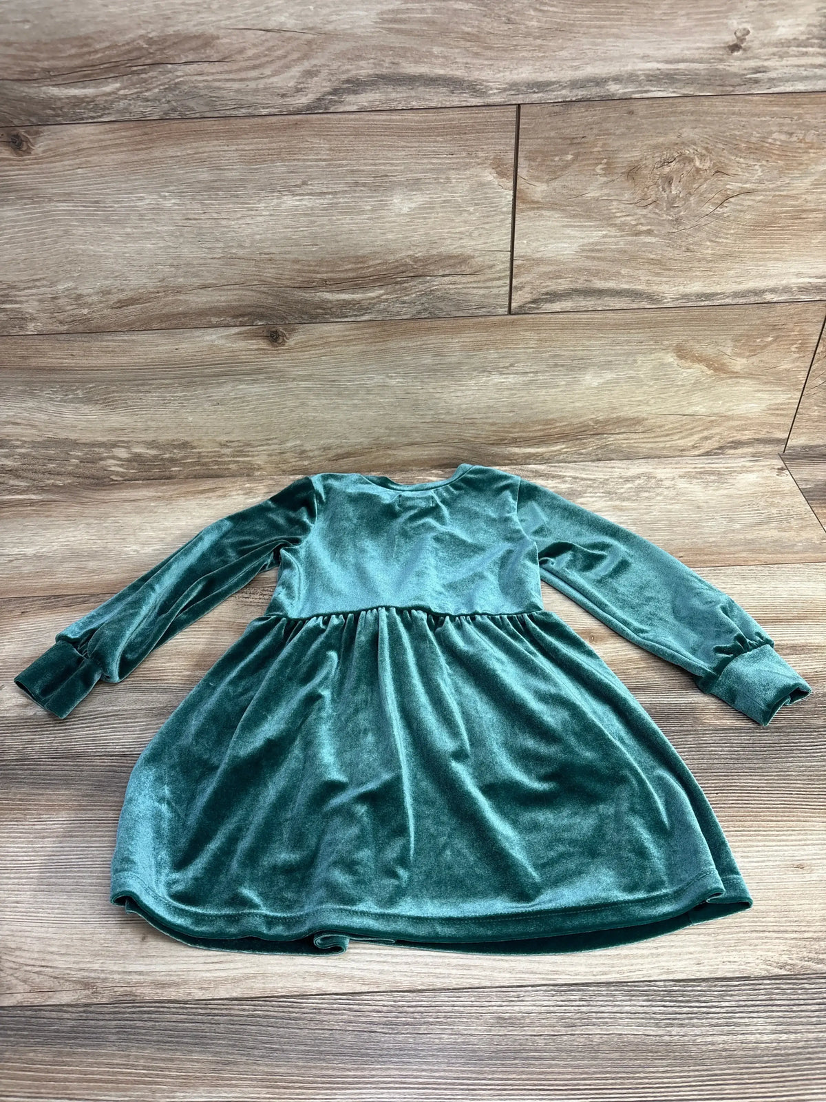 Flat lay of Cat & Jack emerald velvet long-sleeve toddler dress (4T) showing front bow detail on wooden floor