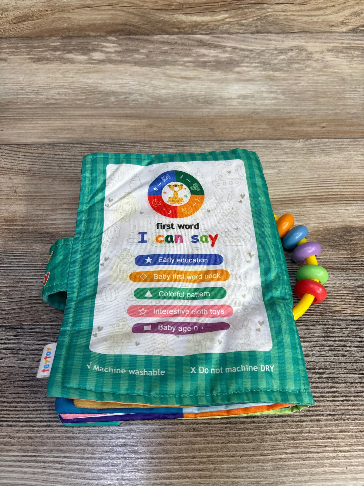 Front view of Teytoy First Word I Can Say Soft Activity Book showing green plaid cover and attached teething rings