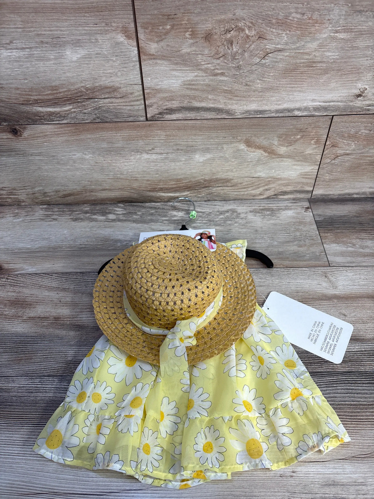 Top view of Blueberi Boulevard two piece floral dress and straw sun hat set showcasing yellow floral fabric on a wood floor