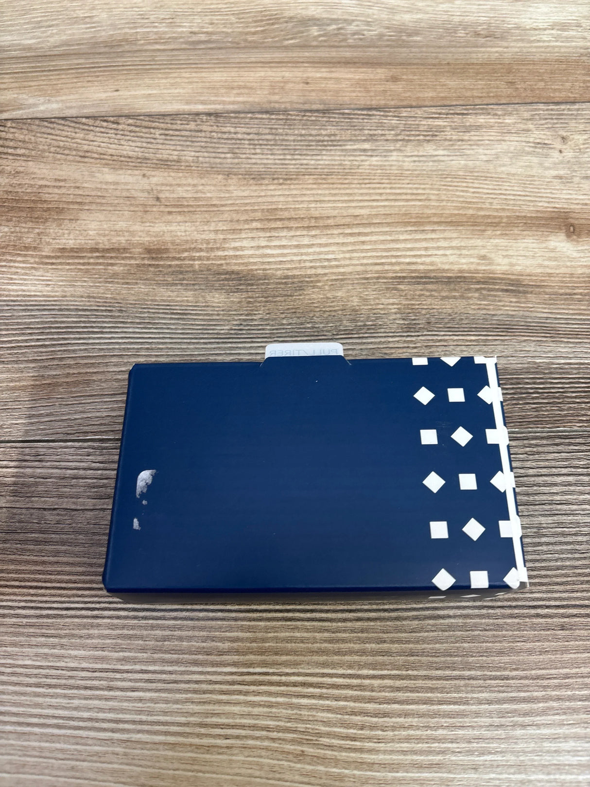 Navy blue box with white geometric pattern on right side on a wooden surface