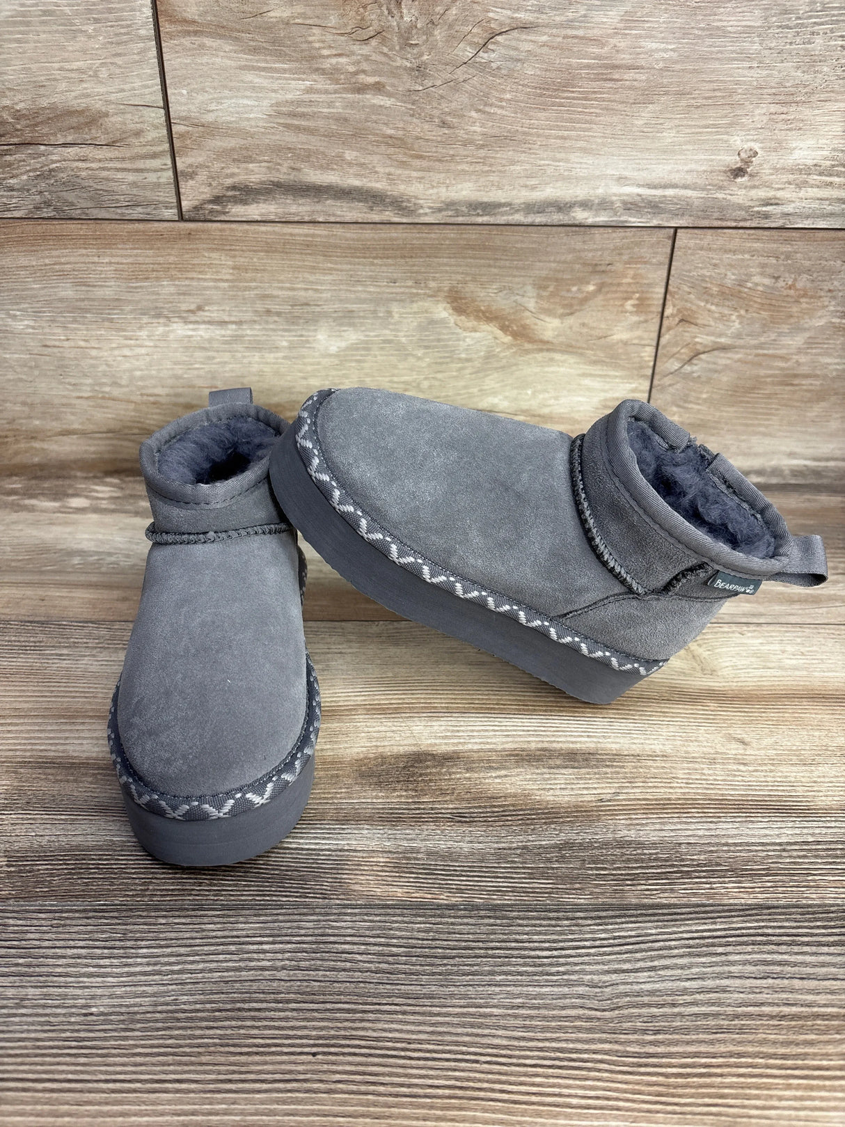 Gray suede children's boots with faux fur lining on wooden background