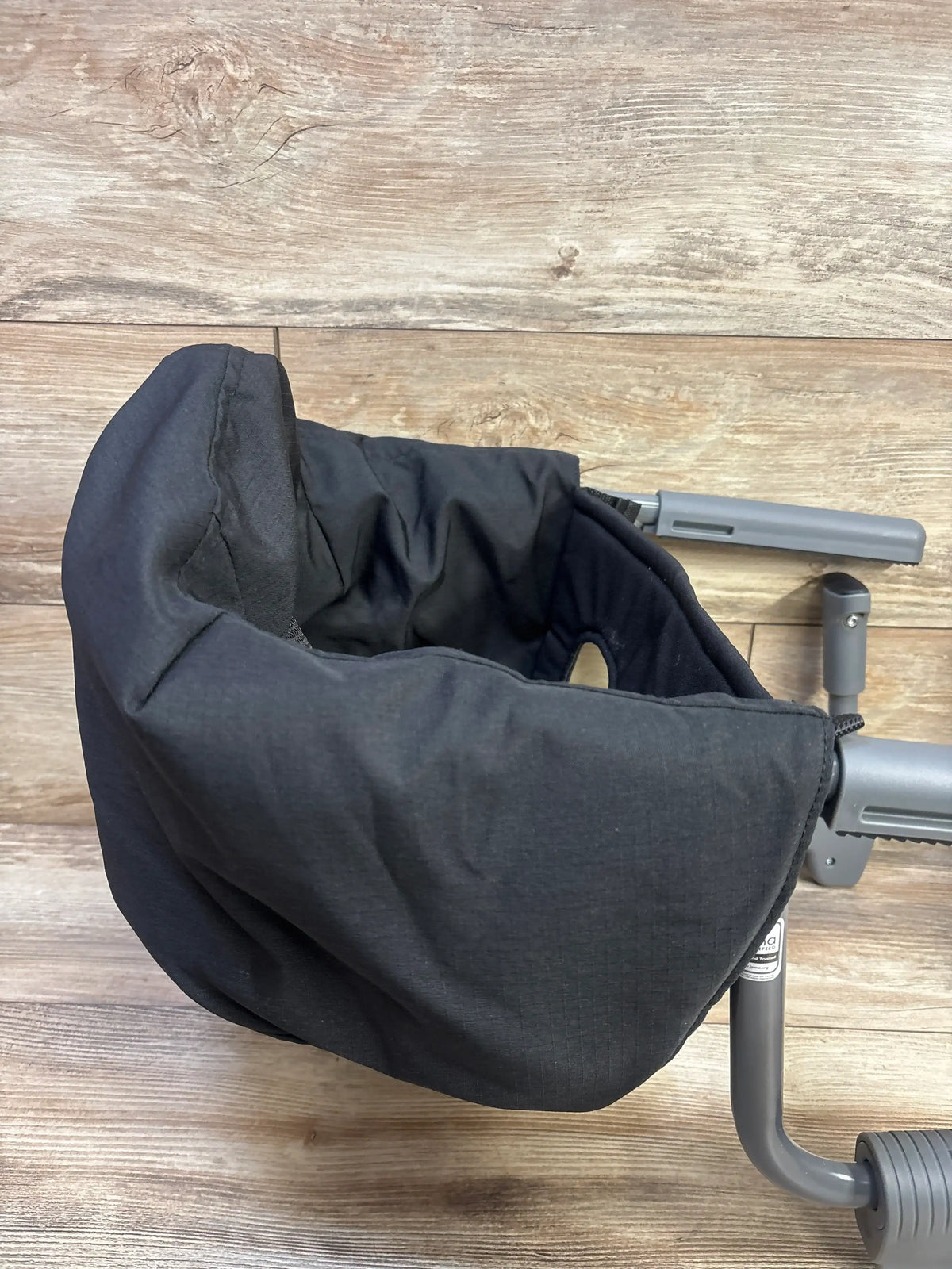 Top view of Chicco FastLock Hook On Chair in black showcasing padded seat and table clamps on a wood floor