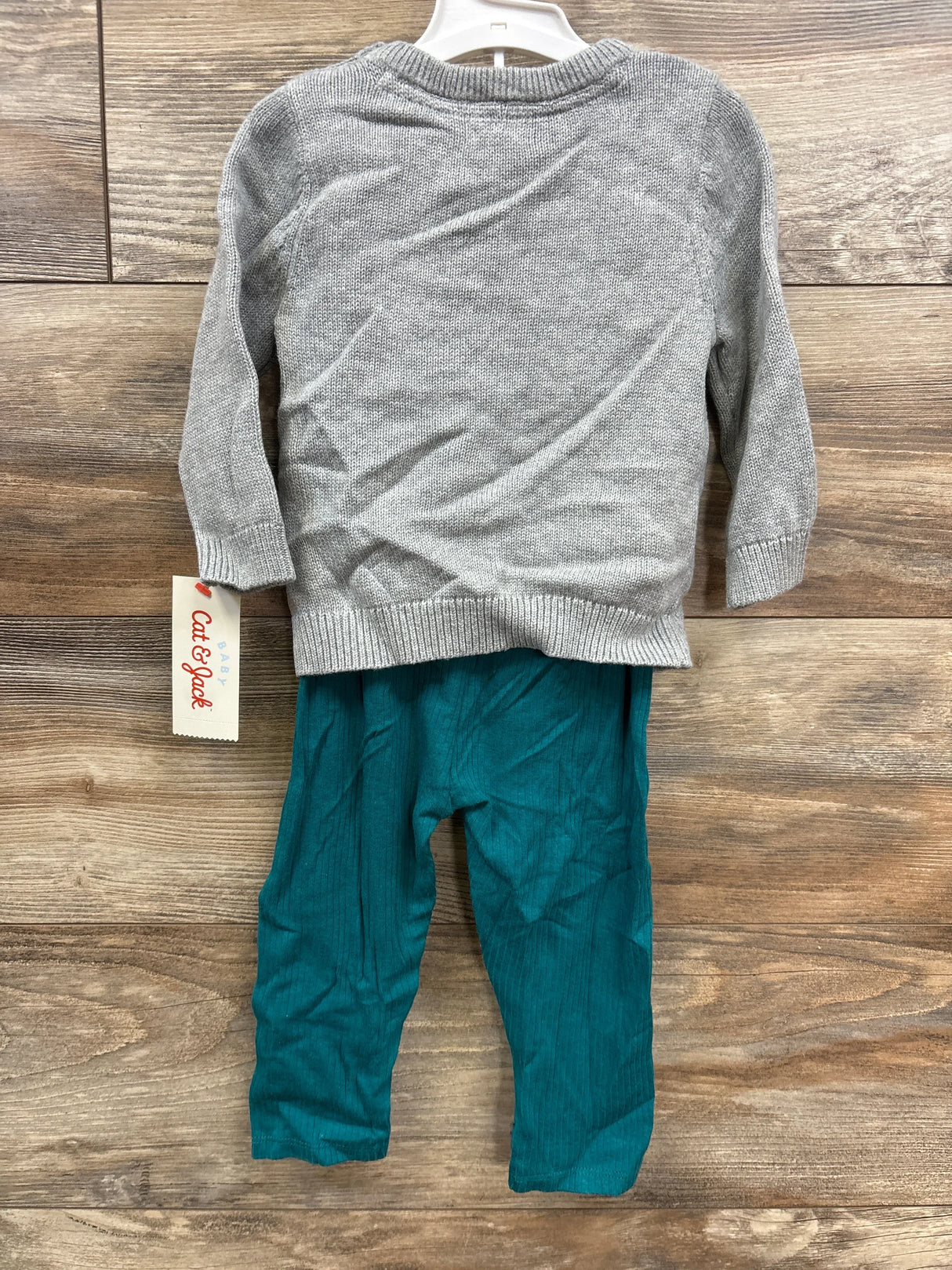 Baby outfit with light gray long-sleeve sweater and teal ribbed pants on wooden floor
