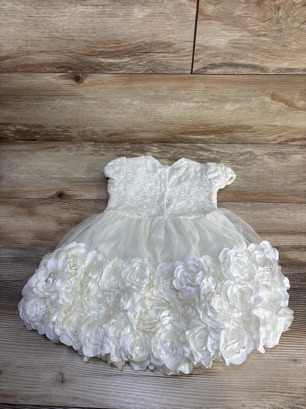 Top-down view of white Nannette lace rosette toddler dress showcasing lace bodice, tulle skirt and layered rosette hem on wood floor