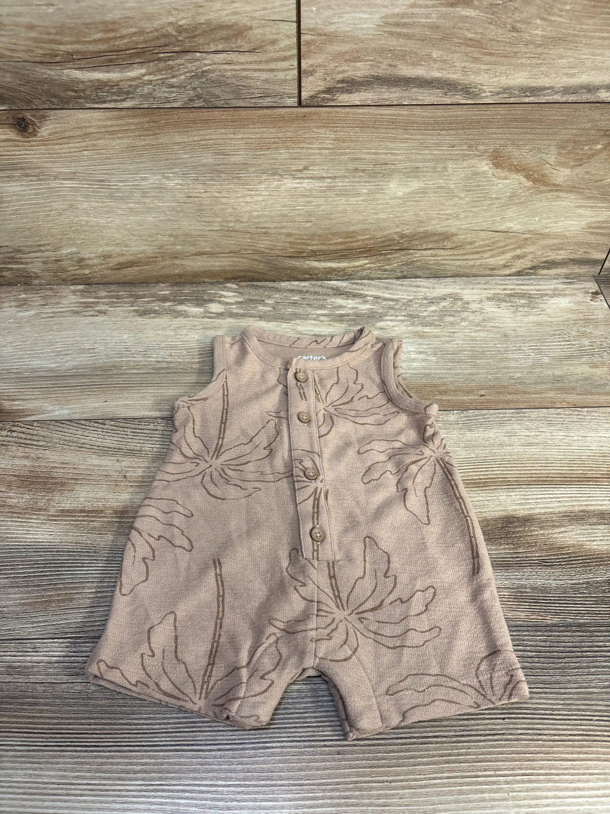Front view of brown Just One You Henley shortie romper with buttoned neckline and floral pattern on wood-look background