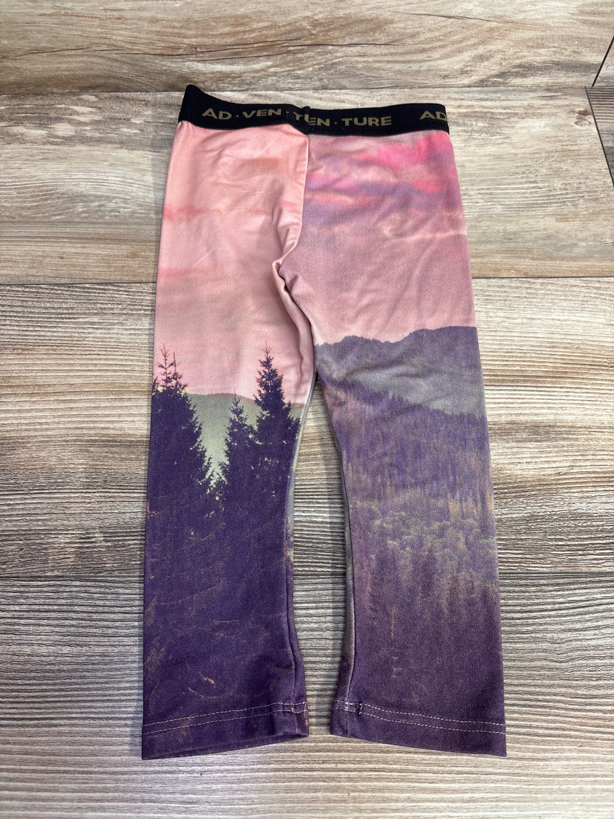 Kids leggings with pink and purple mountain forest print and ADVENTURE waistband on wood background