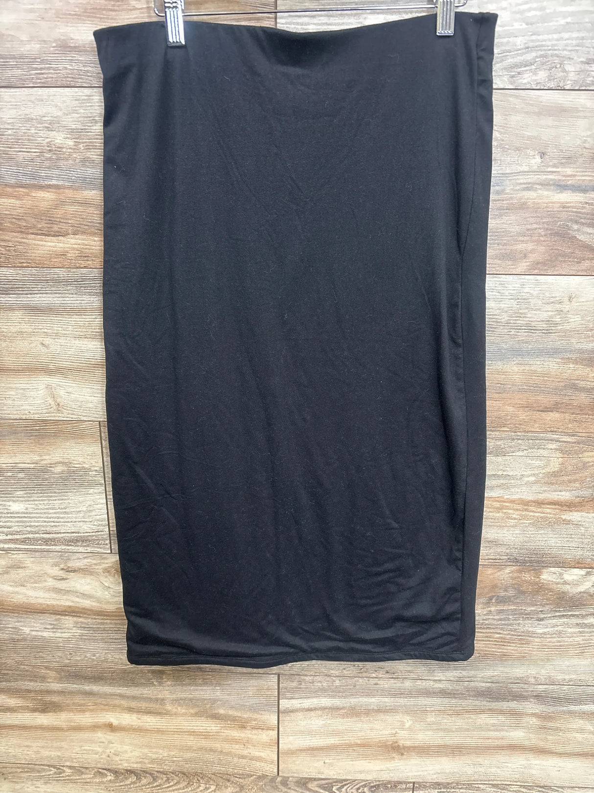 Black maternity skirt hanging on wooden wall background, part of kids and maternity resale clothing