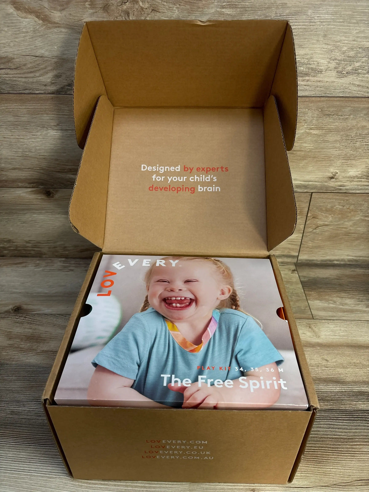 Top view of Lovevery The Free Spirit Play Kit showing a smiling child on the cover inside an open cardboard box
