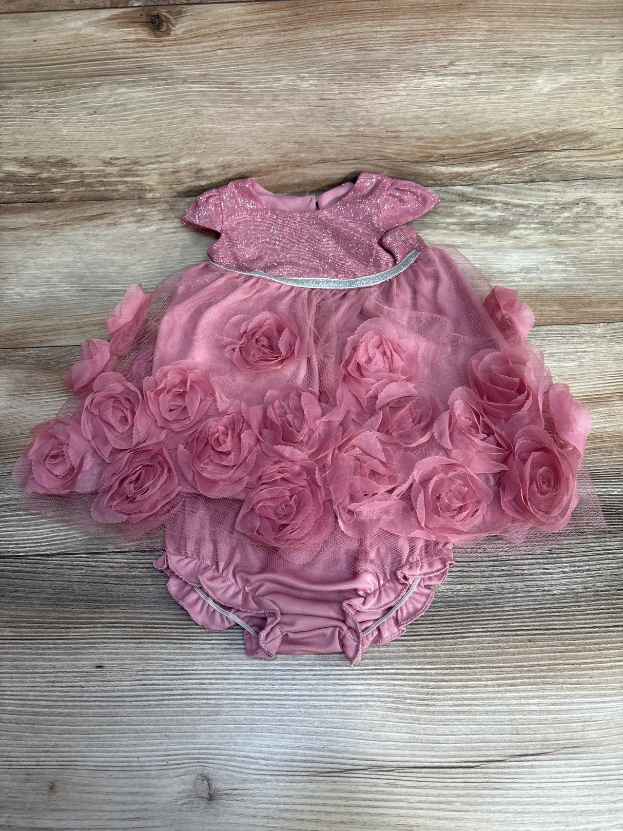 Pink baby dress with glittery top and 3D floral tulle skirt on wooden background