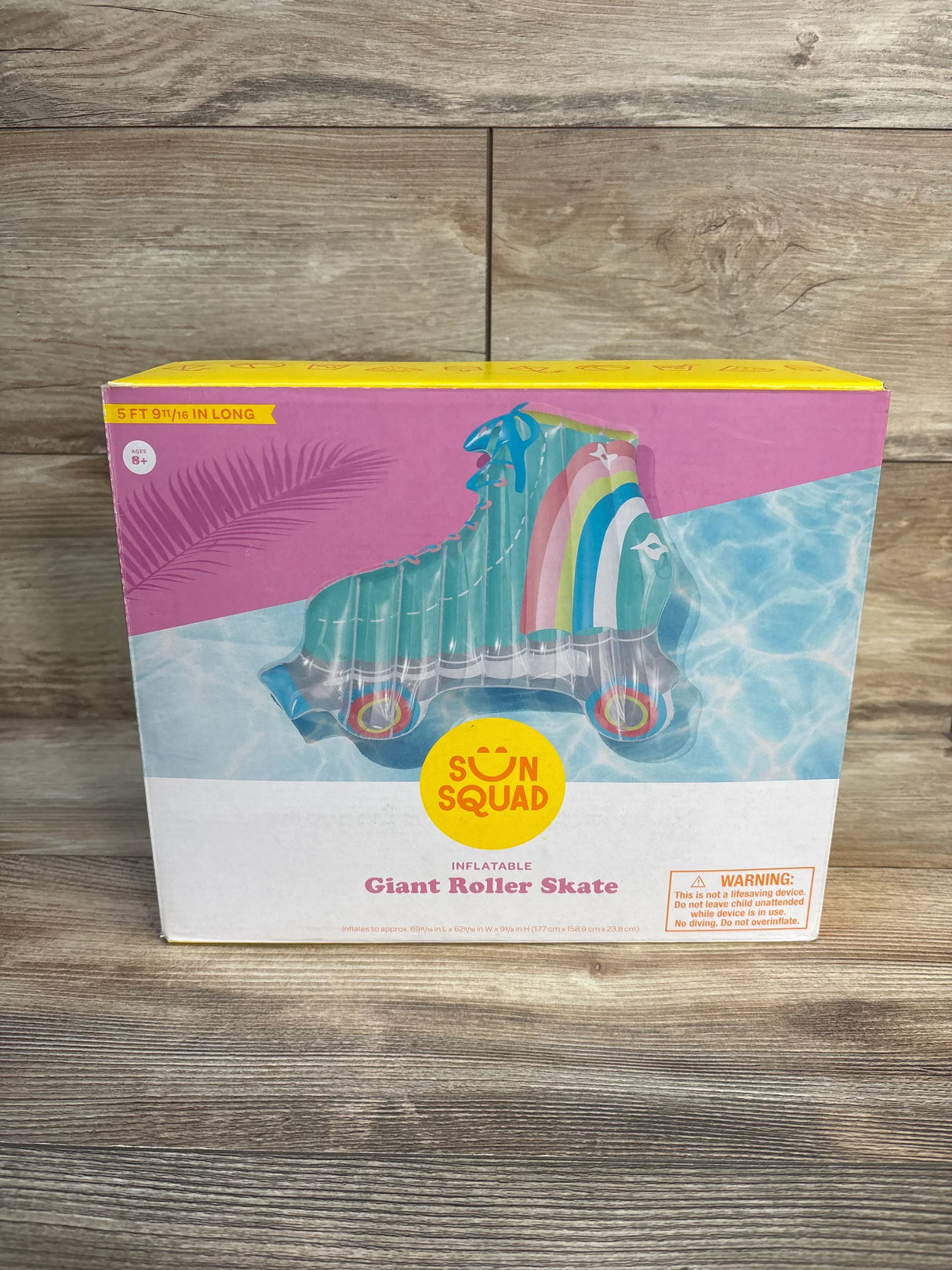 Sun Squad inflatable giant roller skate pool float in box, rainbow design, wood background