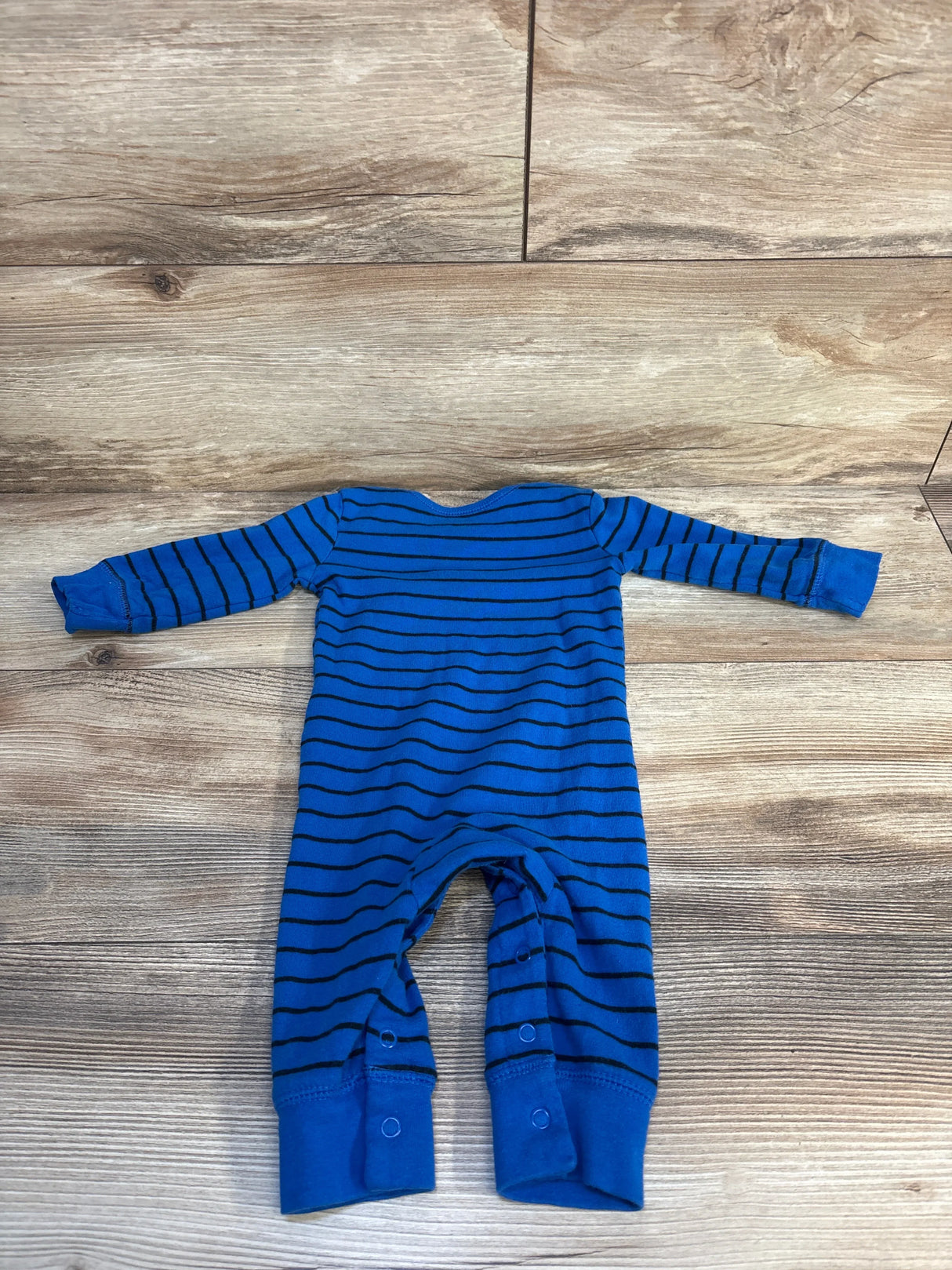 Blue striped long sleeve baby romper with snaps, laid flat on wood floor