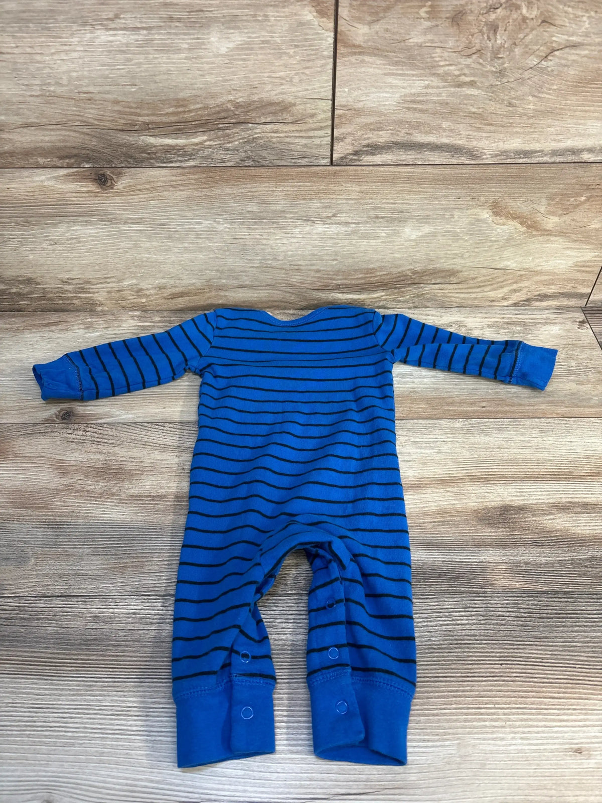 Blue striped long sleeve baby romper with snaps, laid flat on wood floor
