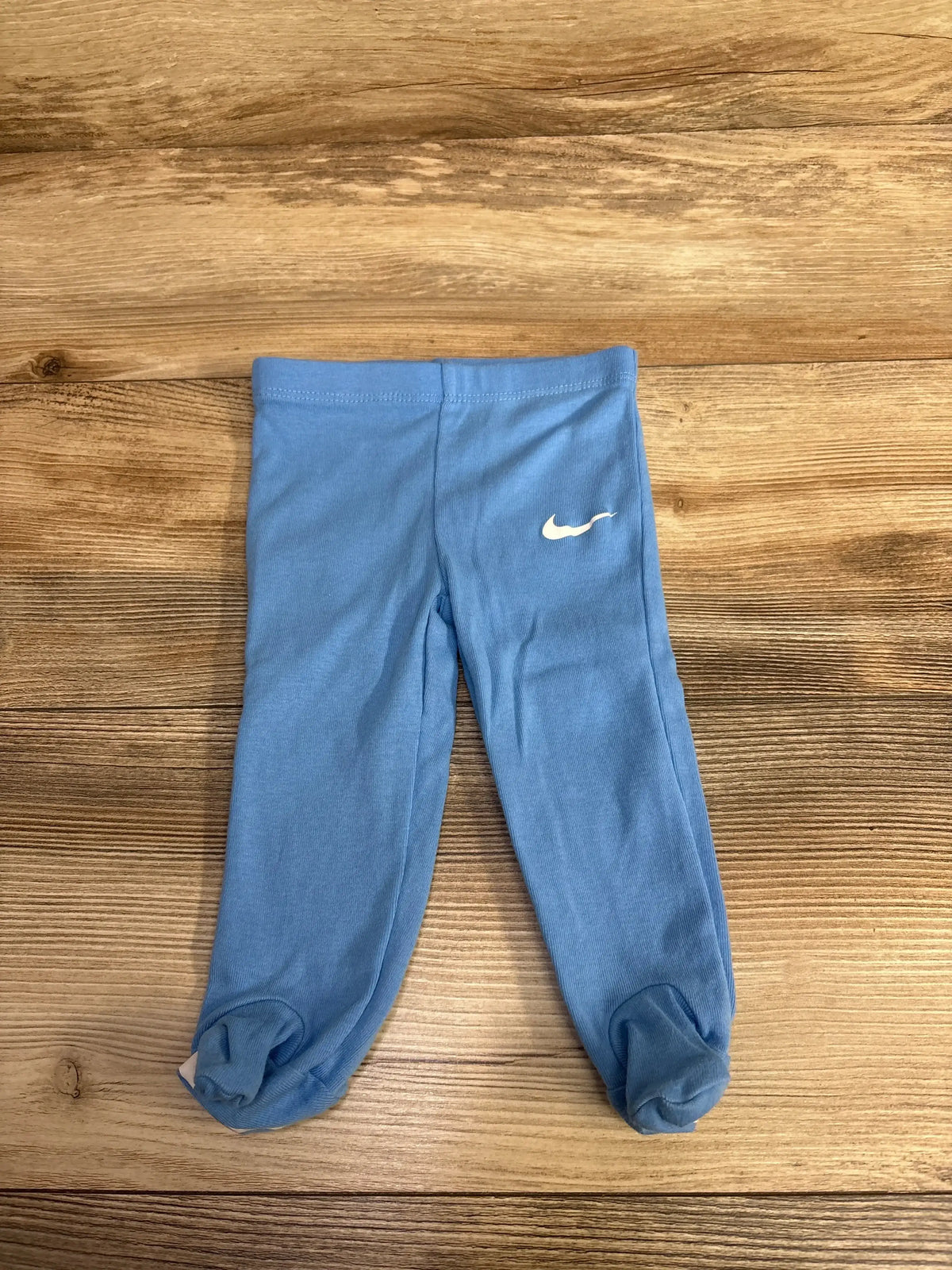 Blue baby leggings with white Nike logo on wooden surface, children's activewear