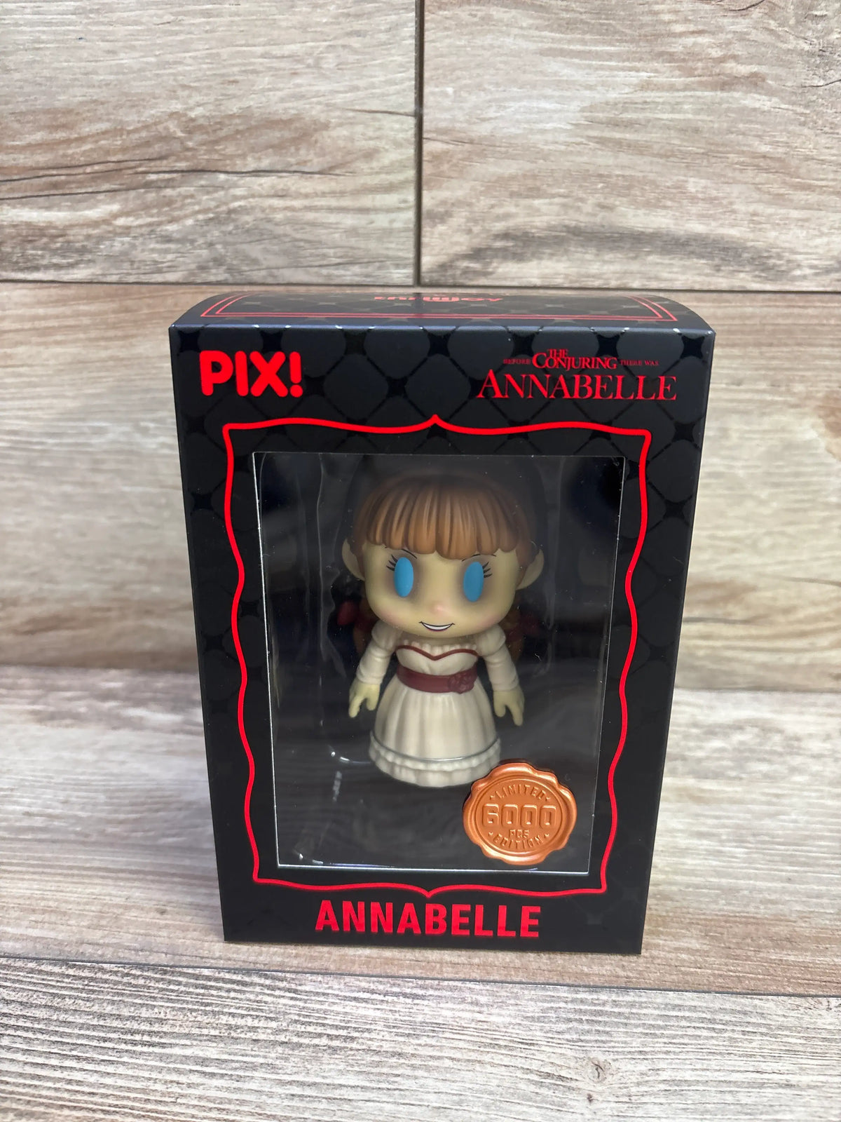 Front view of Thrilljoy Pix The Conjuring Annabelle vinyl figure showcasing blue eyes and white dress in black and red packaging