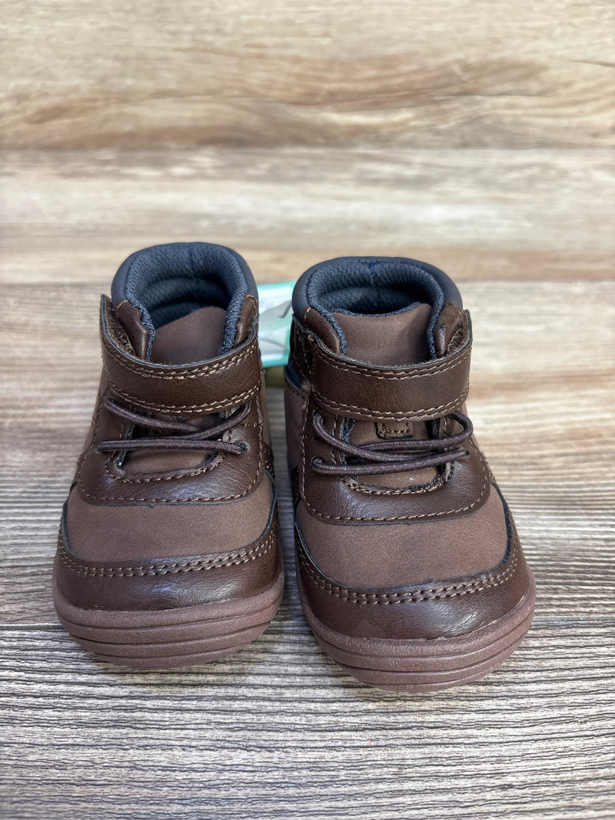Pair of brown toddler shoes with velcro and laces on wooden surface