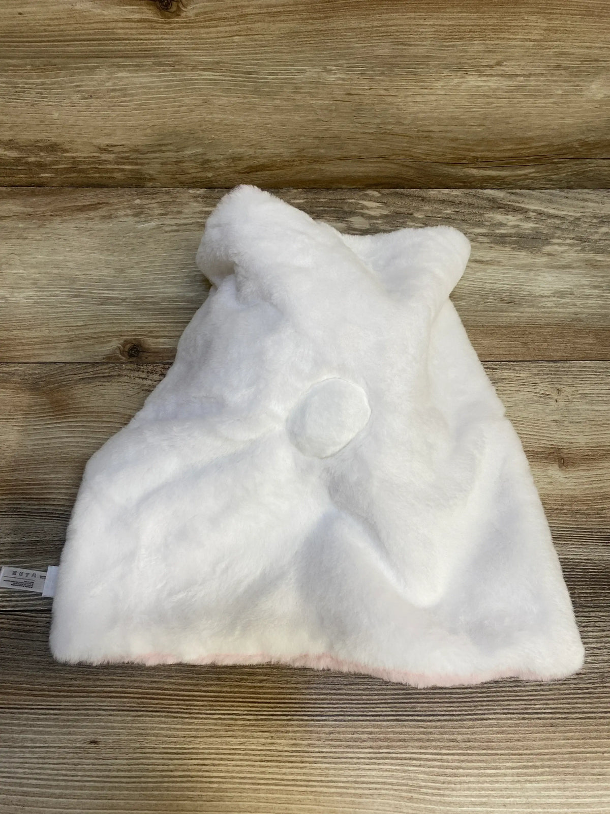 Back view of DreamGro Buddy Blankie pink unicorn blanket showing white plush back, horn nub, and pink trim on wood floor