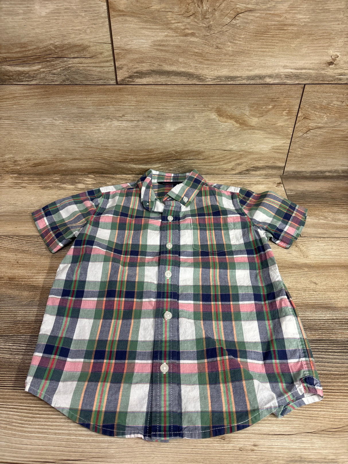 Top-down view of toddler short-sleeve green plaid button-down shirt size 5T showing buttons and collar on wood background