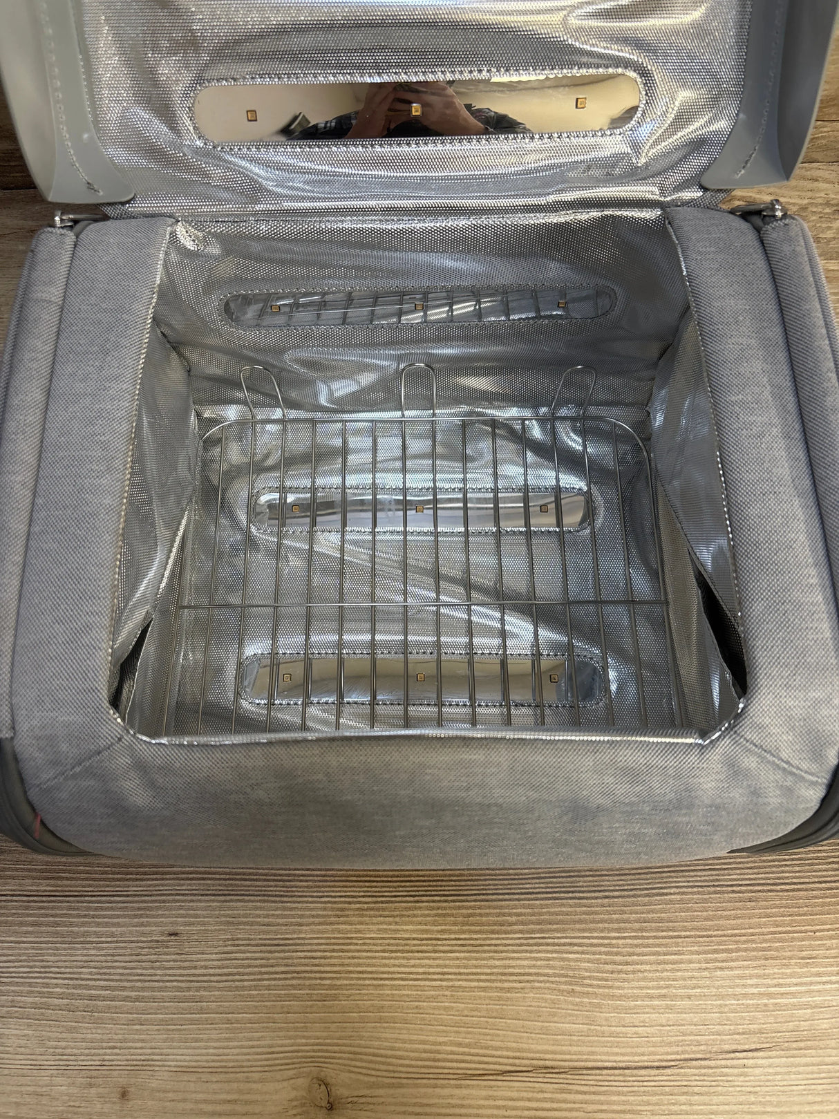 Open interior of Munchkin 59S UV cleaning bag showing reflective lining, LED light strips, and metal rack on wood