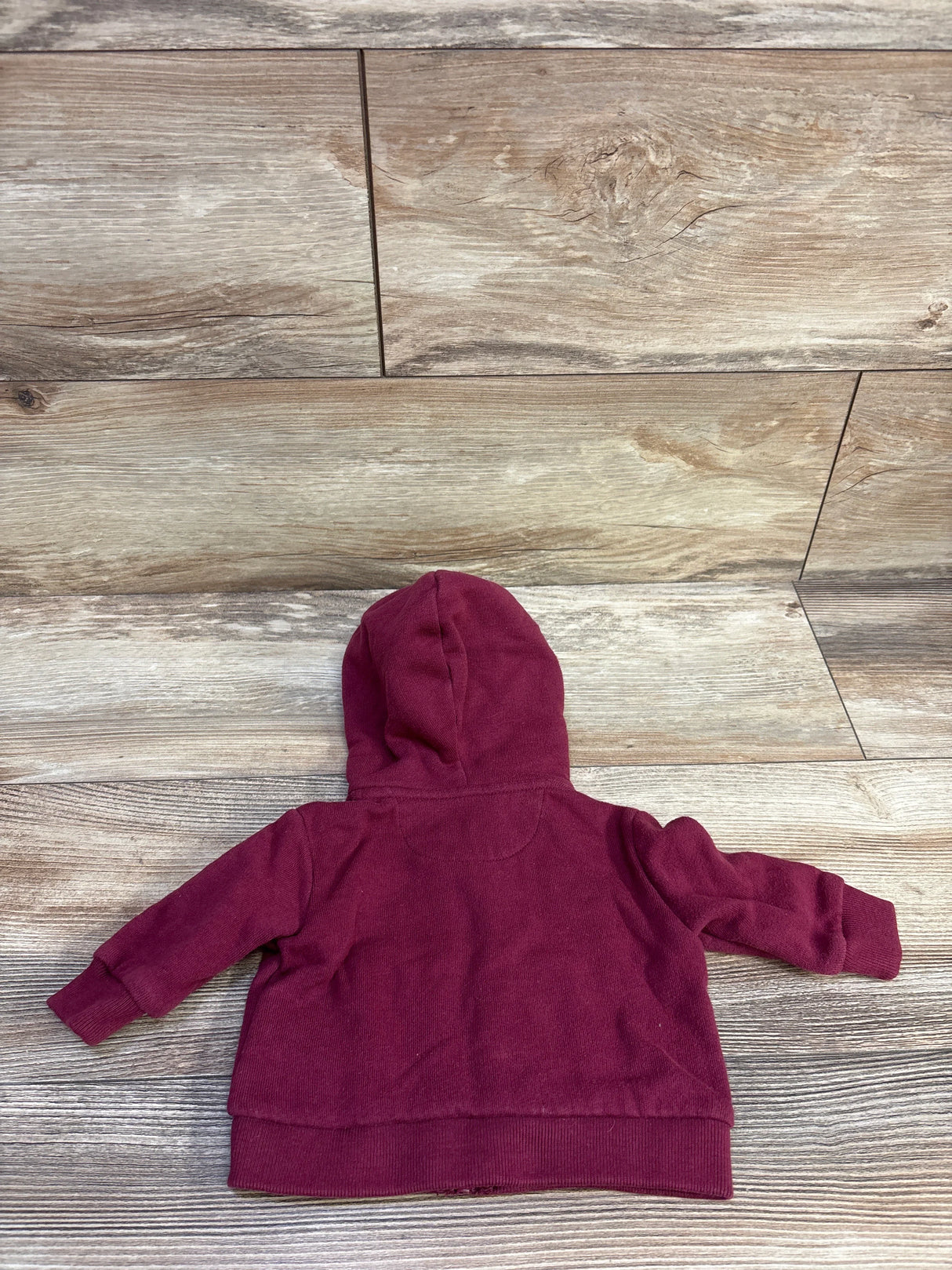Back view of baby Ralph Lauren maroon full-zip hoodie showing hood, long sleeves, and ribbed cuffs and hem on wood floor background