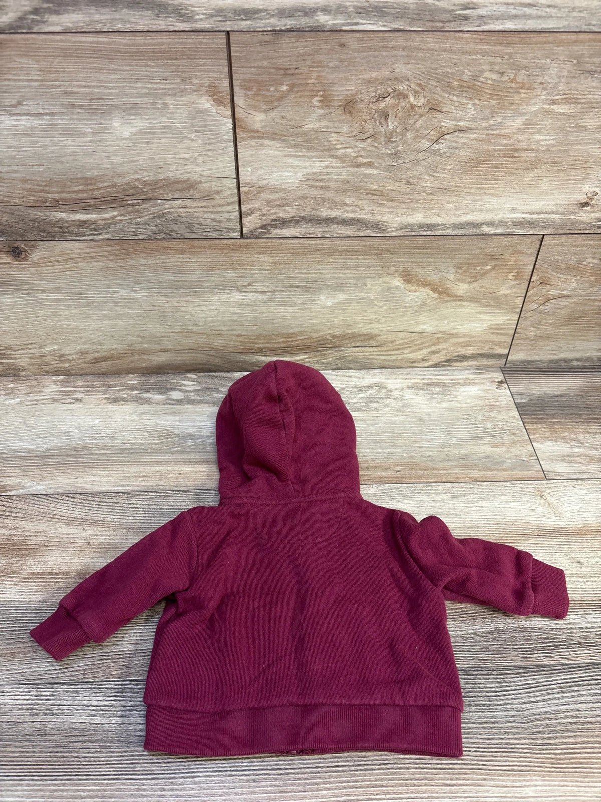 Back view of baby Ralph Lauren maroon full-zip hoodie showing hood, long sleeves, and ribbed cuffs and hem on wood floor background