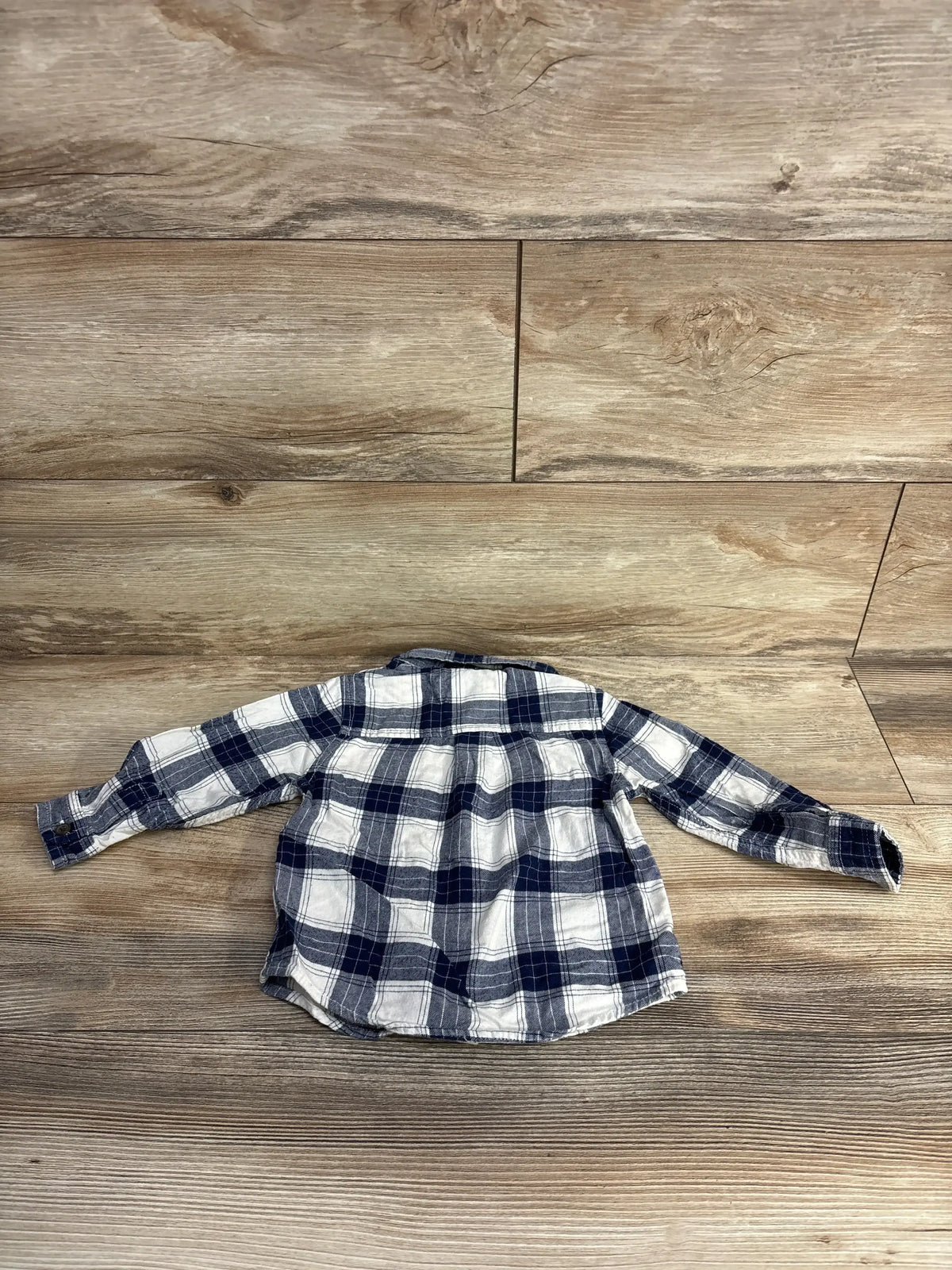 Navy and white plaid long sleeve toddler shirt on wood background