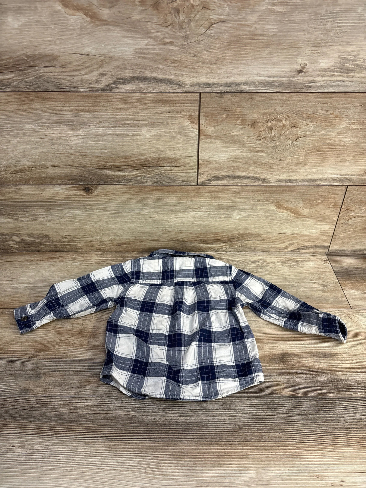Navy and white plaid long sleeve toddler shirt on wood background