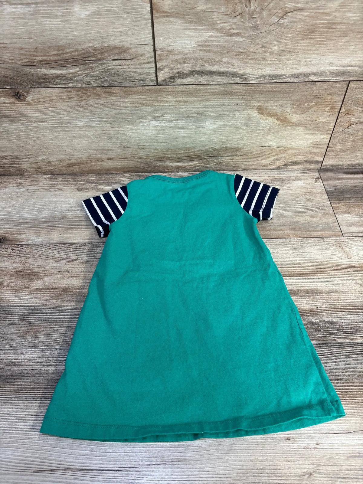 Back view of green Zoologist t-shirt dress showcasing navy-striped short sleeves with a wood floor background