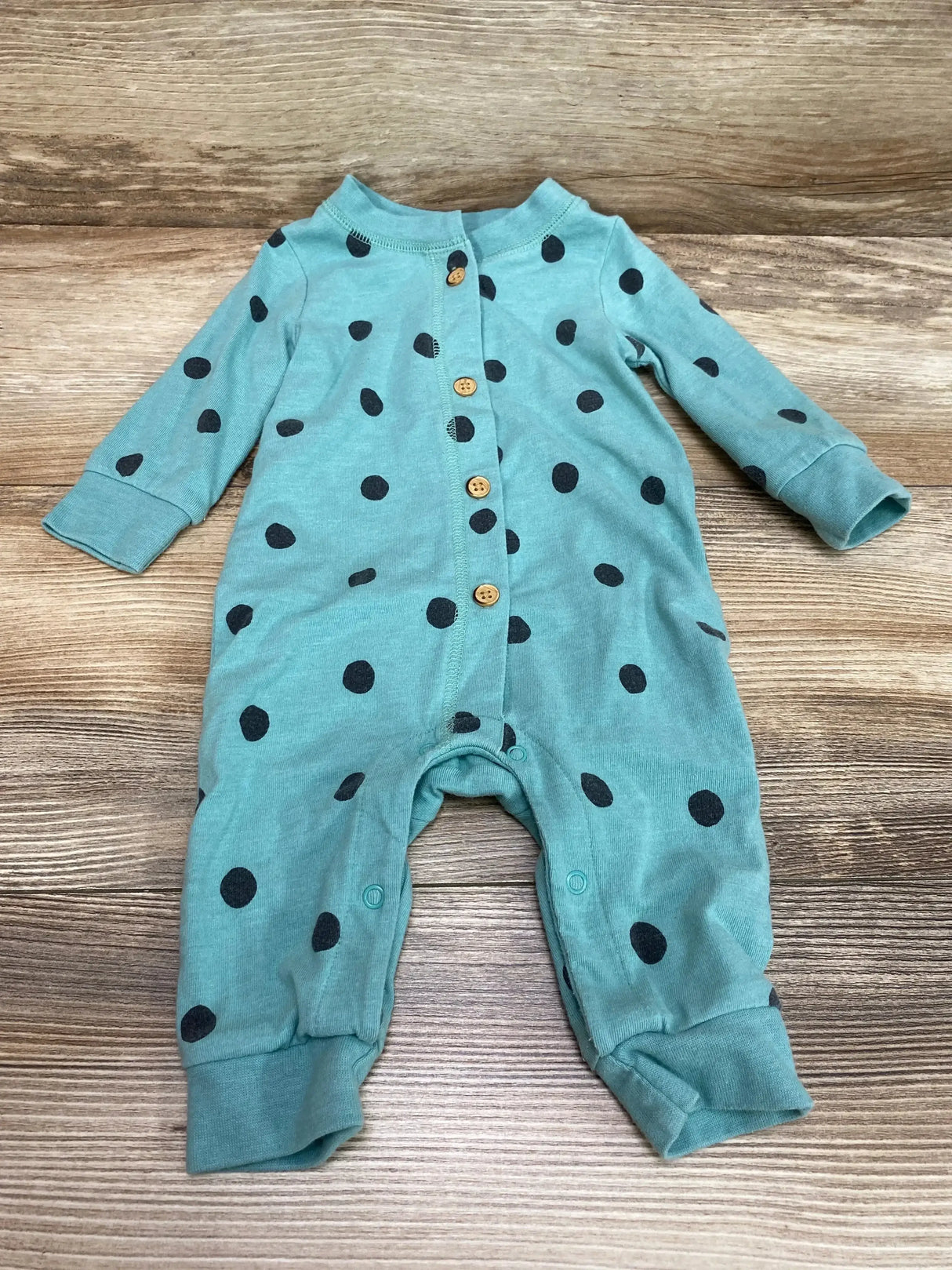 Flat lay of Cat and Jack green polka-dot coverall with wooden front buttons, crotch snaps, cuffed legs on wood background