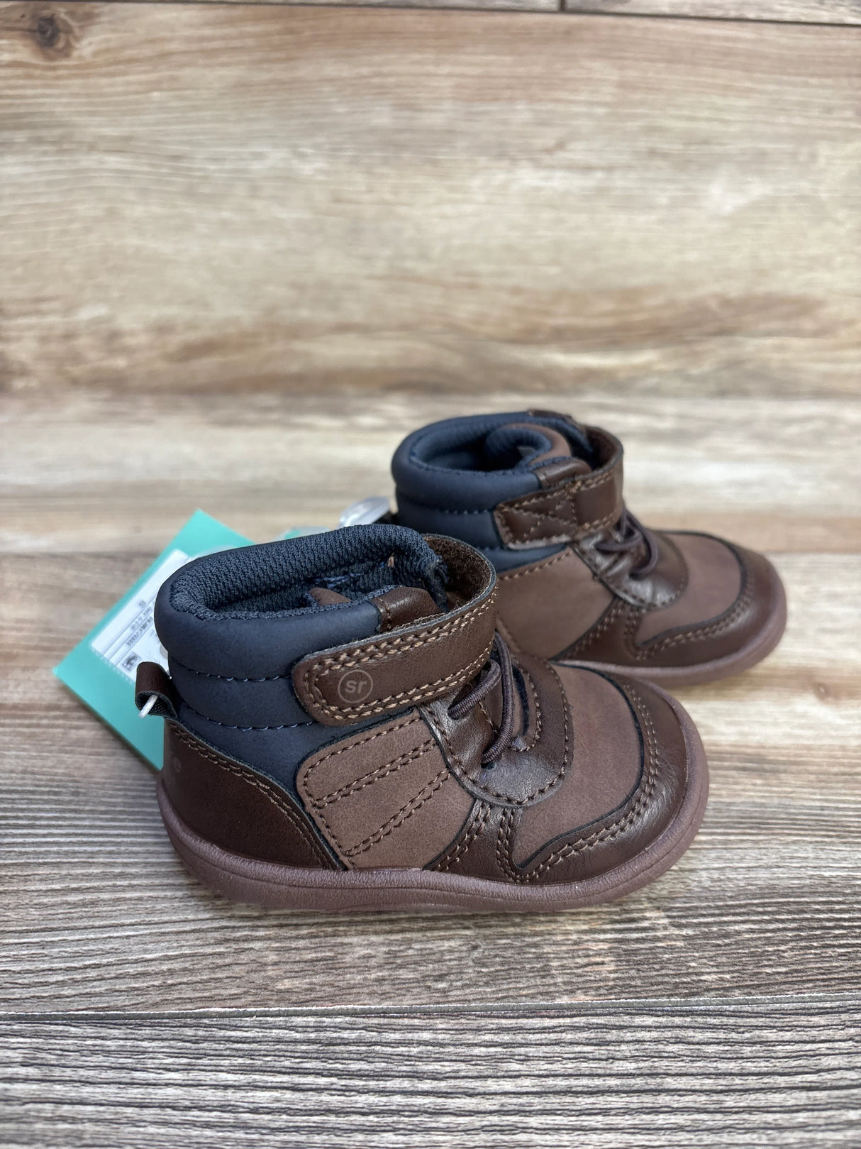 Pair of brown and navy toddler boots with Velcro straps on wood surface