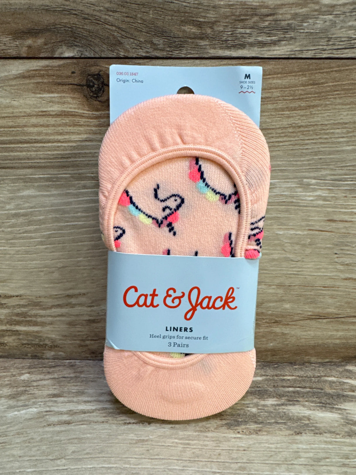 Top-down of Cat and Jack no-show liner socks 3-pack in peach with multicolor pattern and paper band on wood background