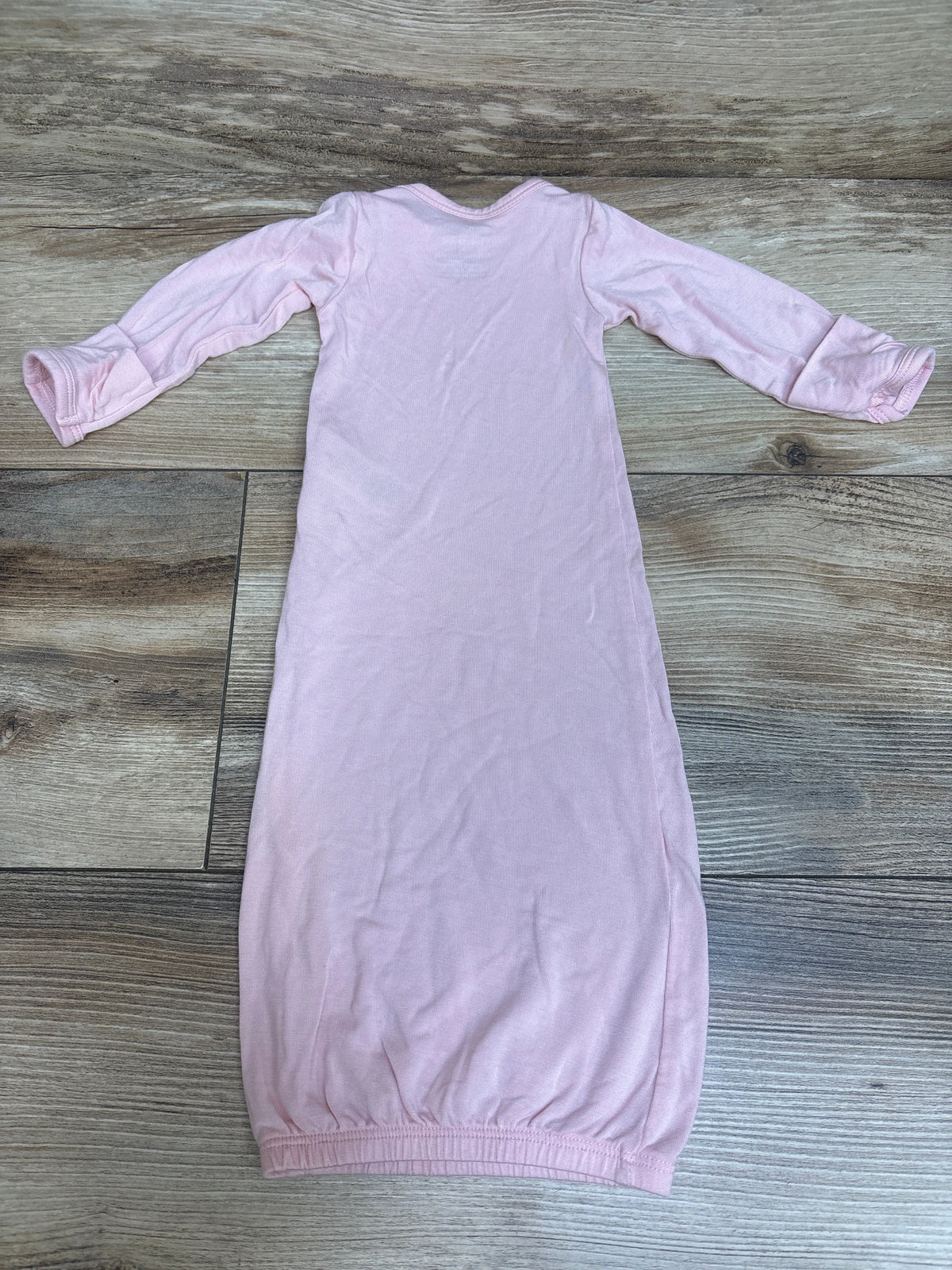 Front view of pink Just One You ComfySoft preemie sleep gown with long sleeves on a wood grain background