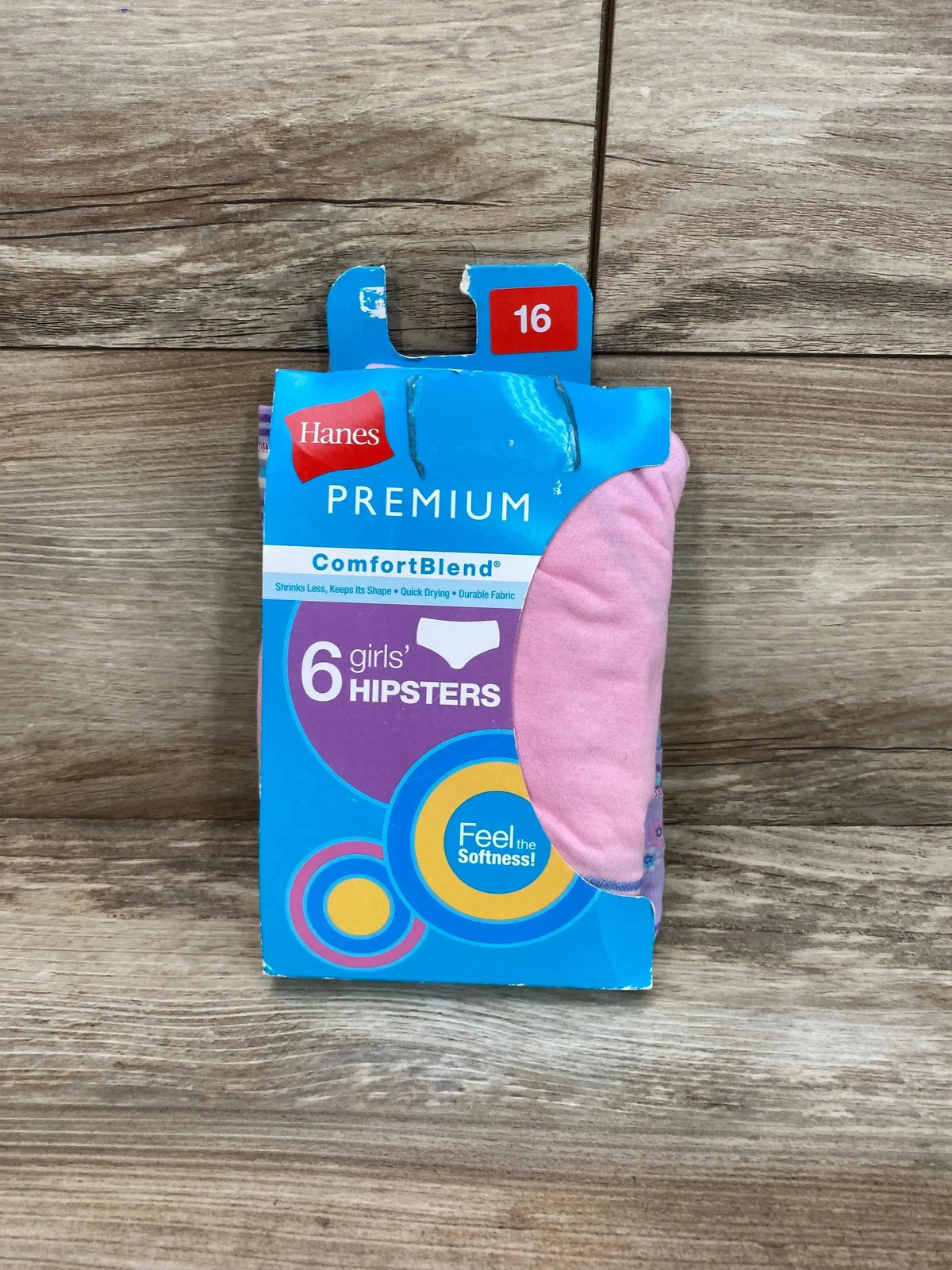 Front of Hanes Premium ComfortBlend girls' hipsters 6-pack packaging, size 16 tag and pink hipster visible on wood background