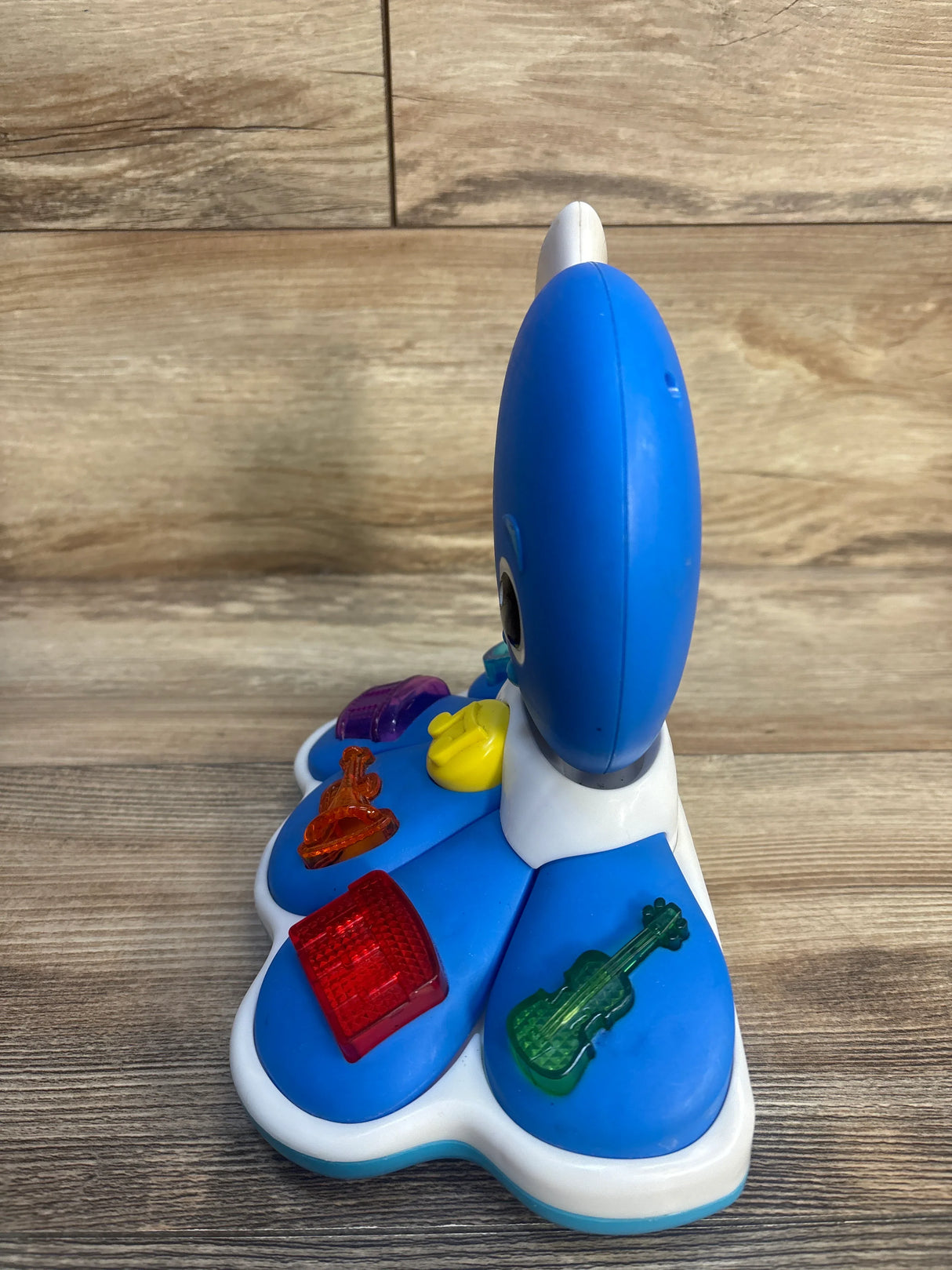 Blue and white children's musical toy with colorful instrument buttons on wood floor