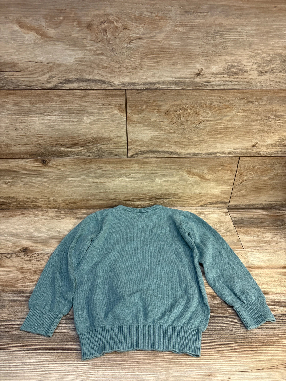 Blue long sleeve kids sweater on wooden background, gently used children's clothing
