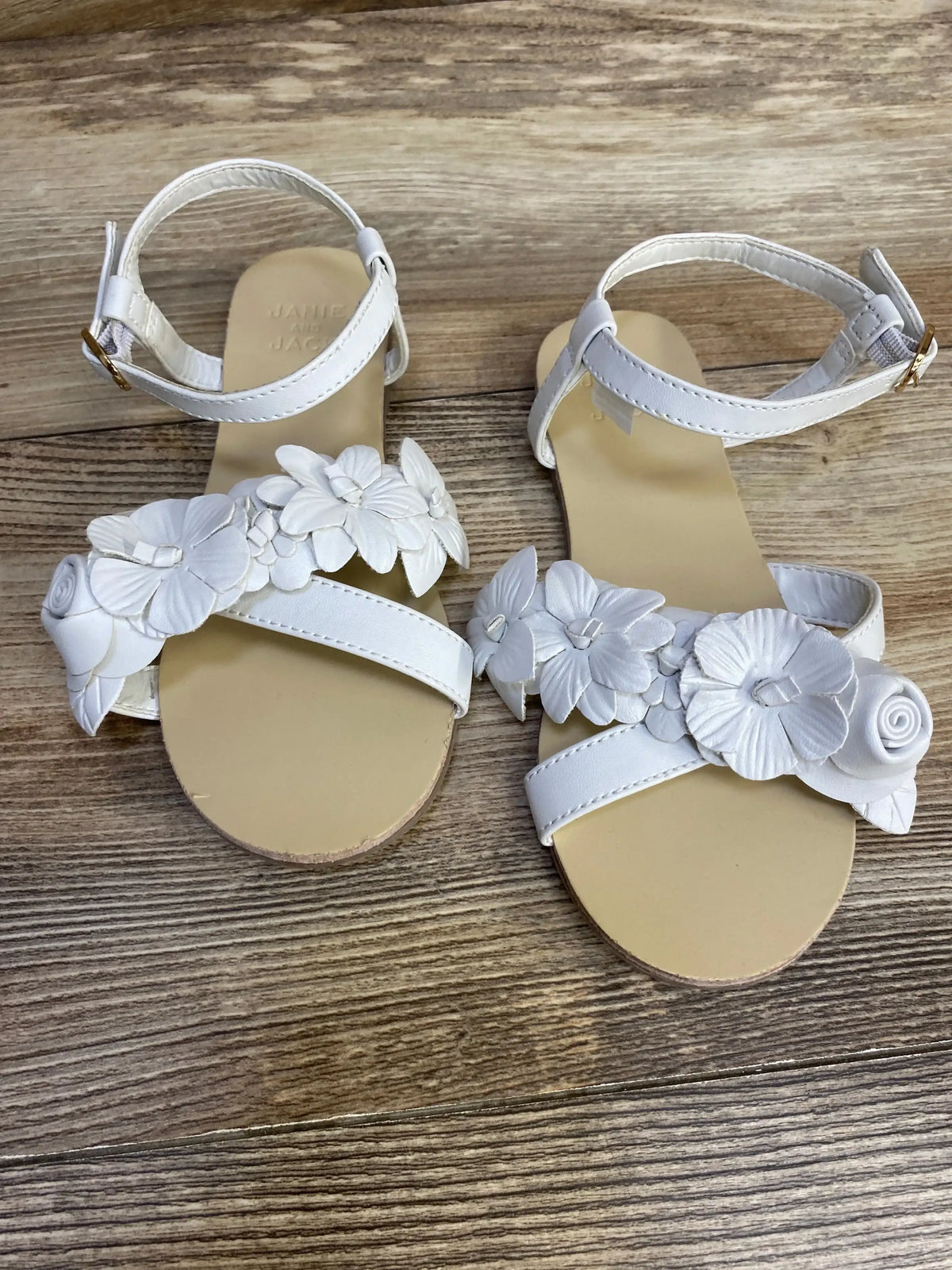 Three-quarter view of Janie and Jack white sandals size 12C showing flower applique and ankle strap