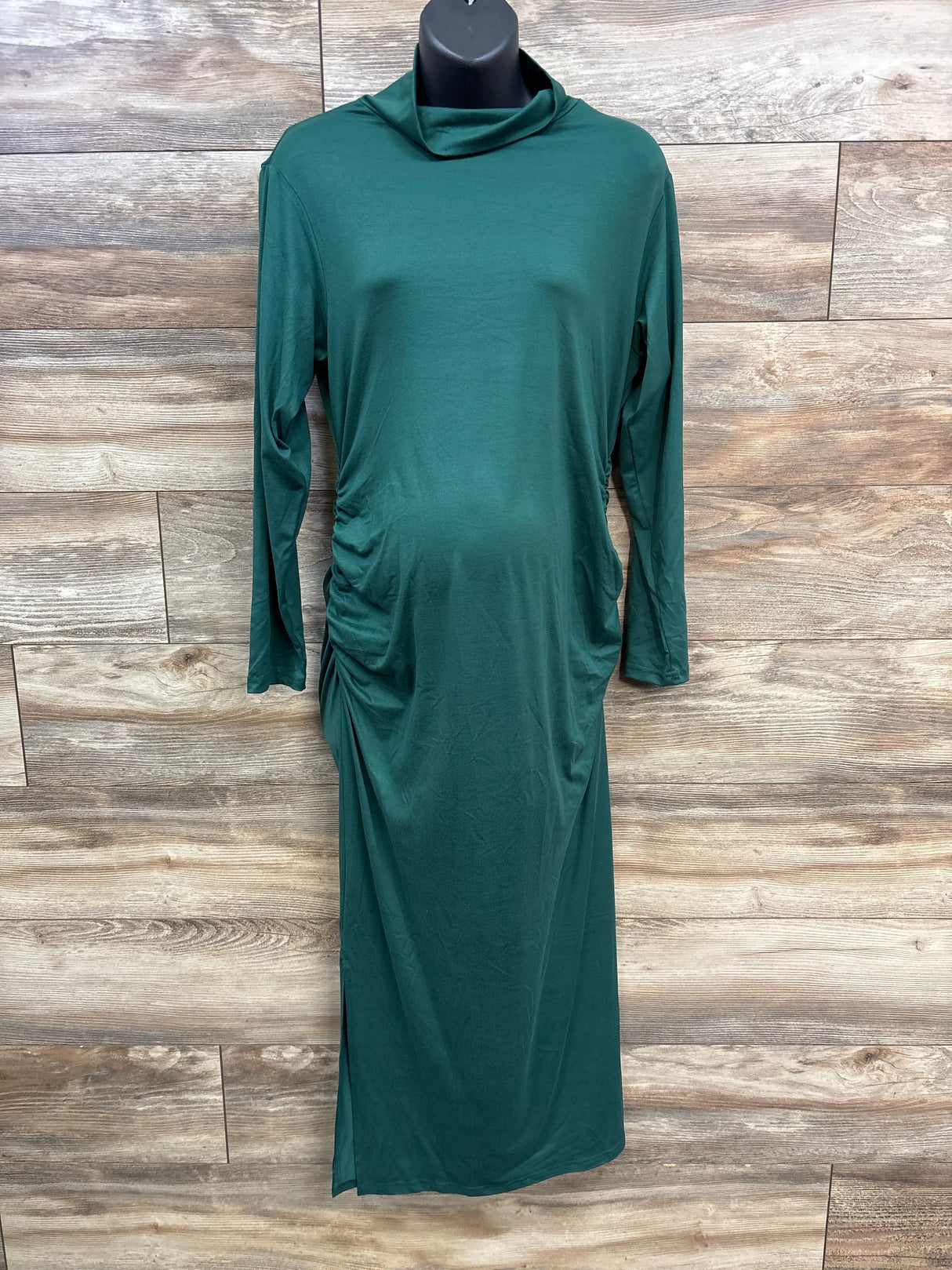 Green long-sleeve maternity dress with side ruching on mannequin against wooden floor background