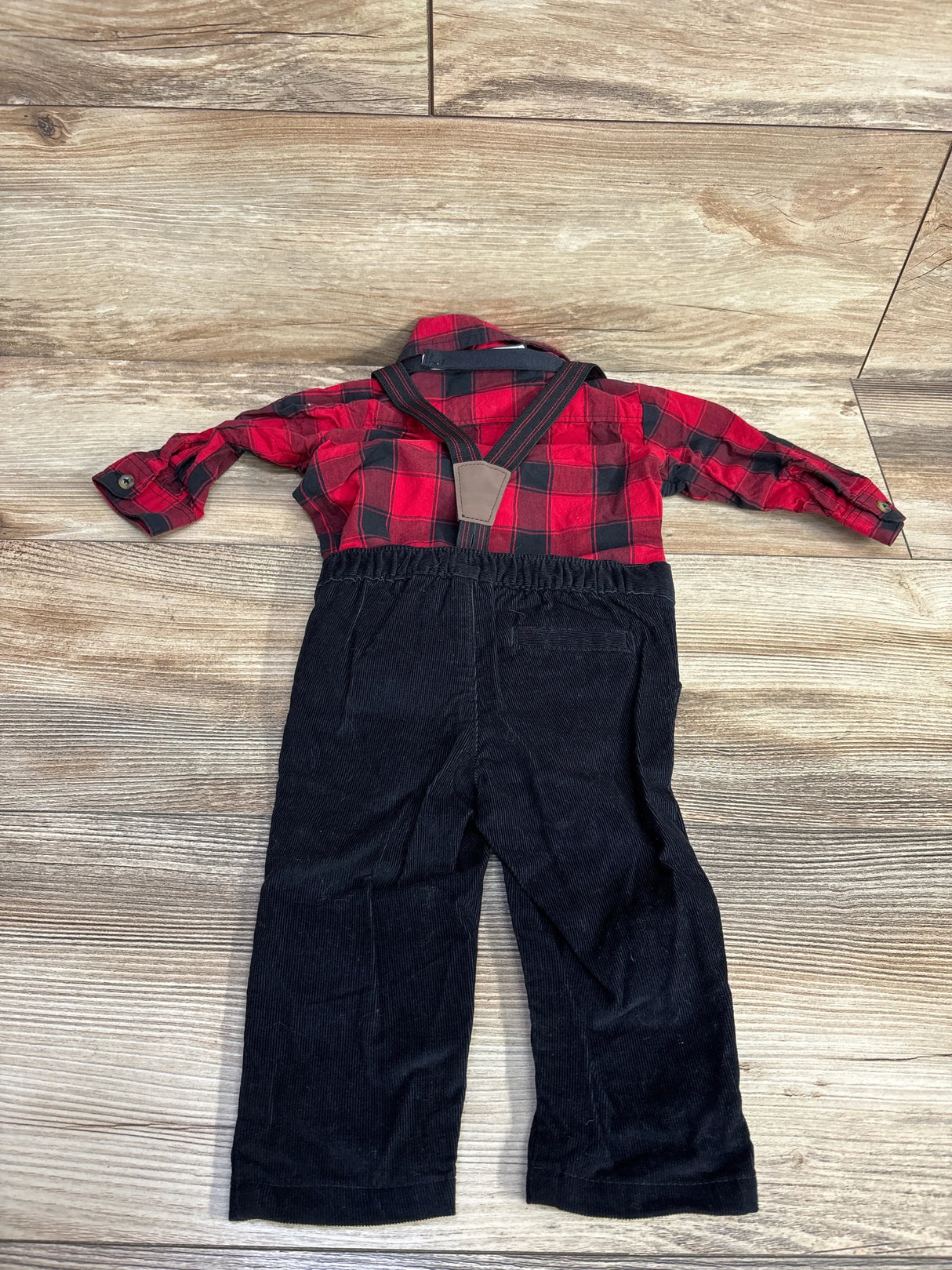 Toddler boy red plaid shirt with black corduroy pants and suspenders on wood floor
