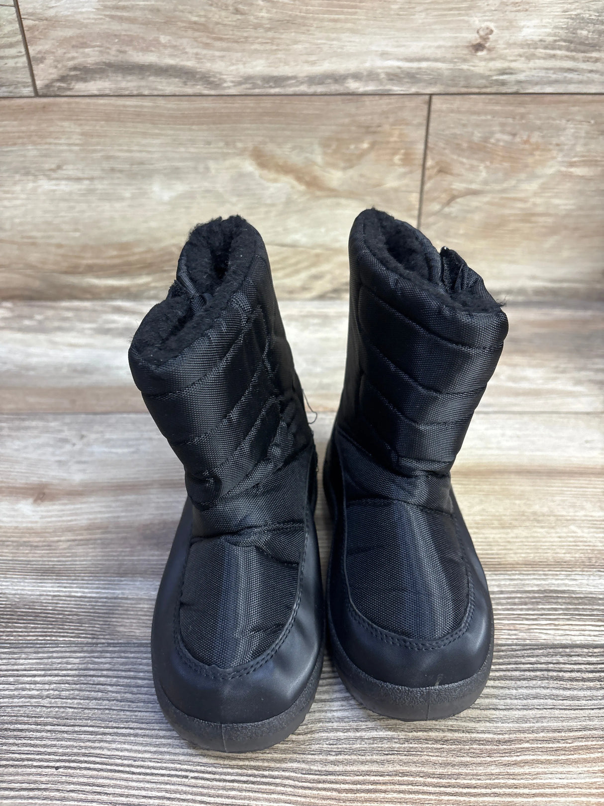 Front view of toddler black snow boots (size 10C) showcasing quilted nylon upper and faux-fur lining on wood background