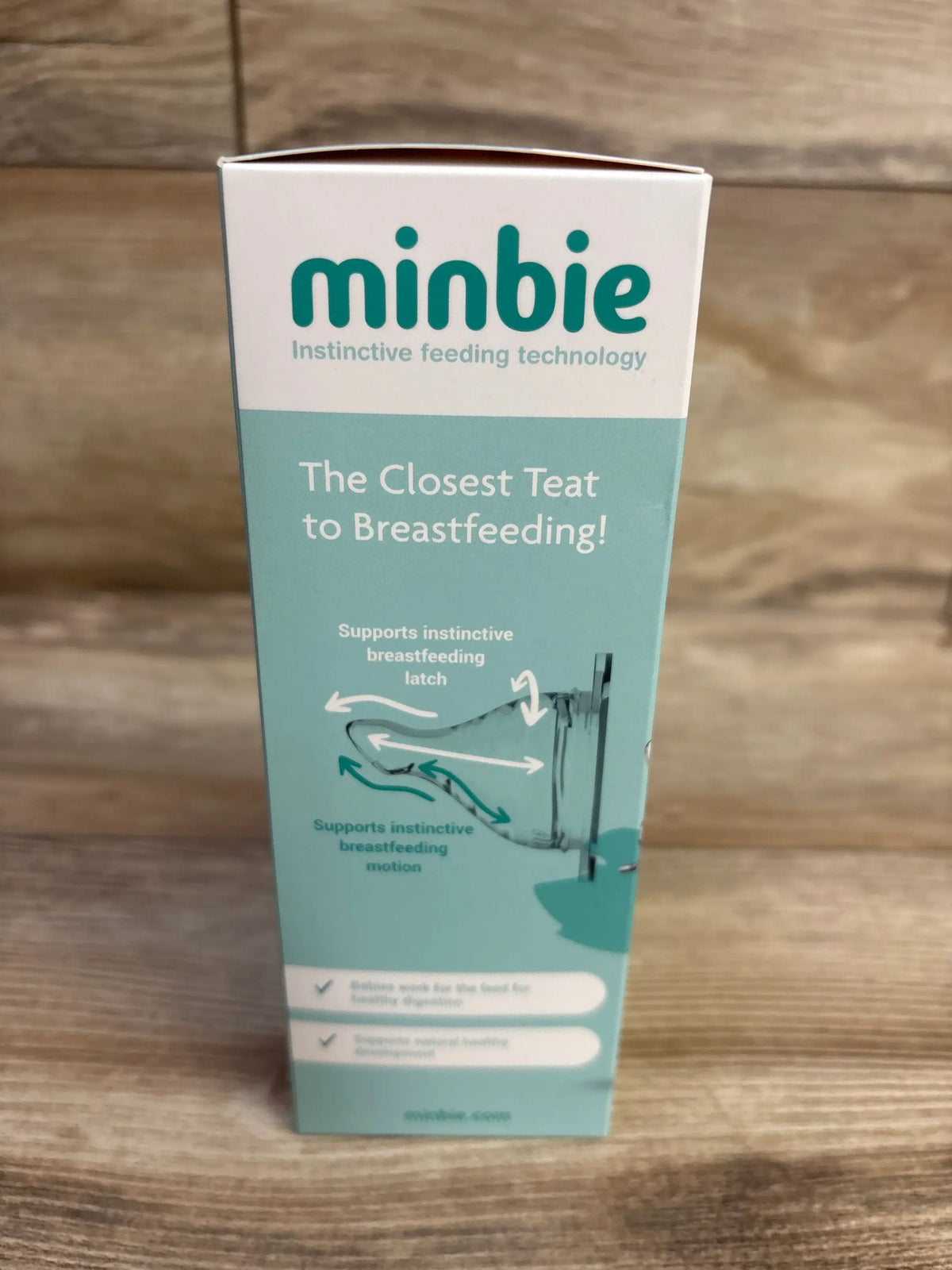 Front view of Minbie 6m+ feeding kit box showing teal packaging with headline The Closest Teat to Breastfeeding on wood backdrop