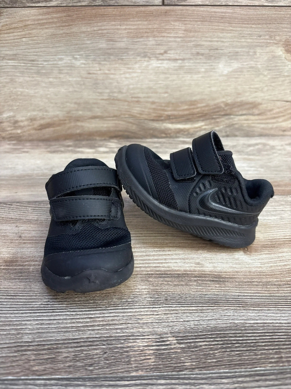 Front view of Nike Star Runner 2 toddler sneakers showcasing double Velcro straps and mesh upper with wood-plank background