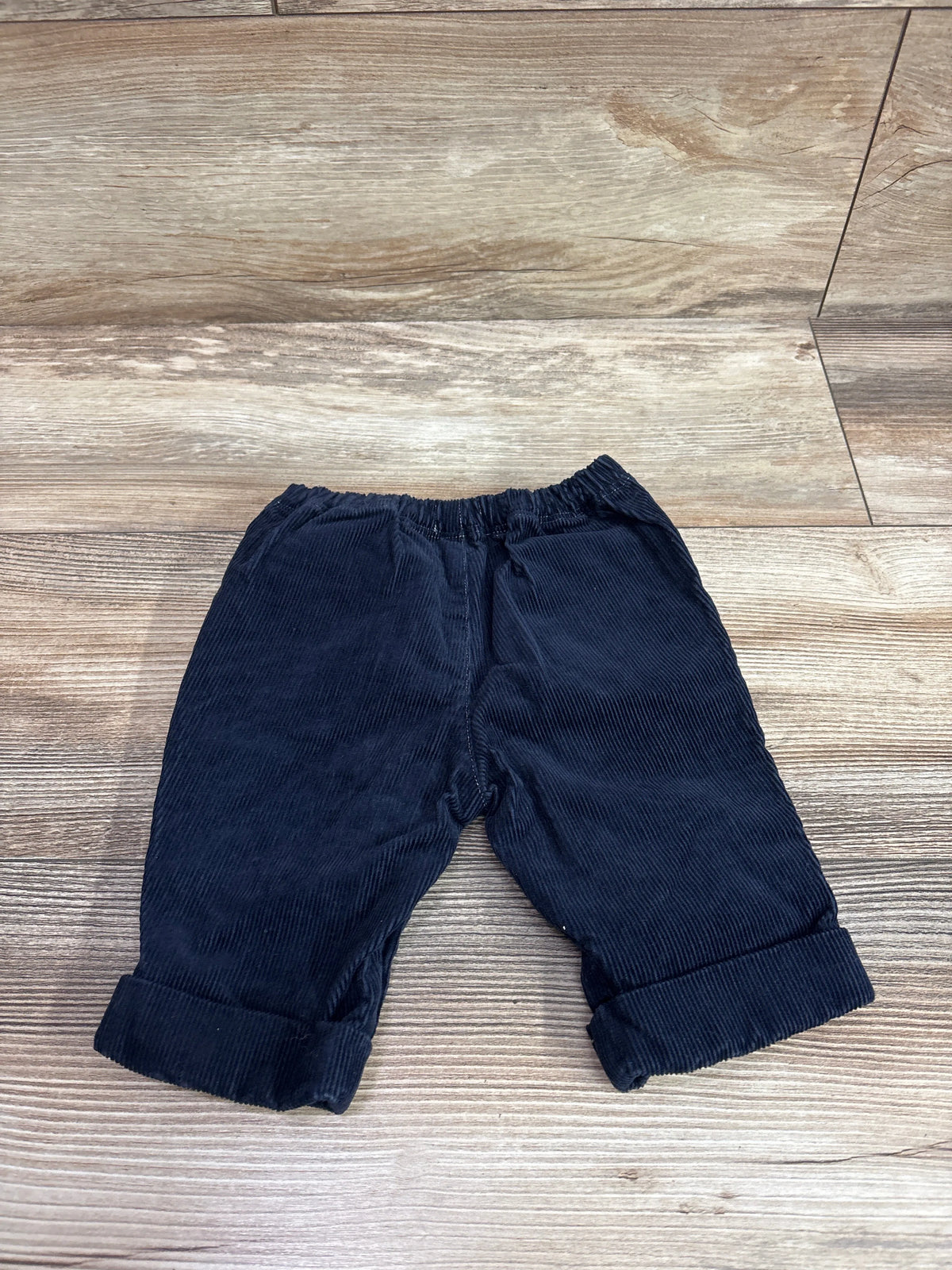 Navy blue corduroy pants for baby size 3m on a wooden background