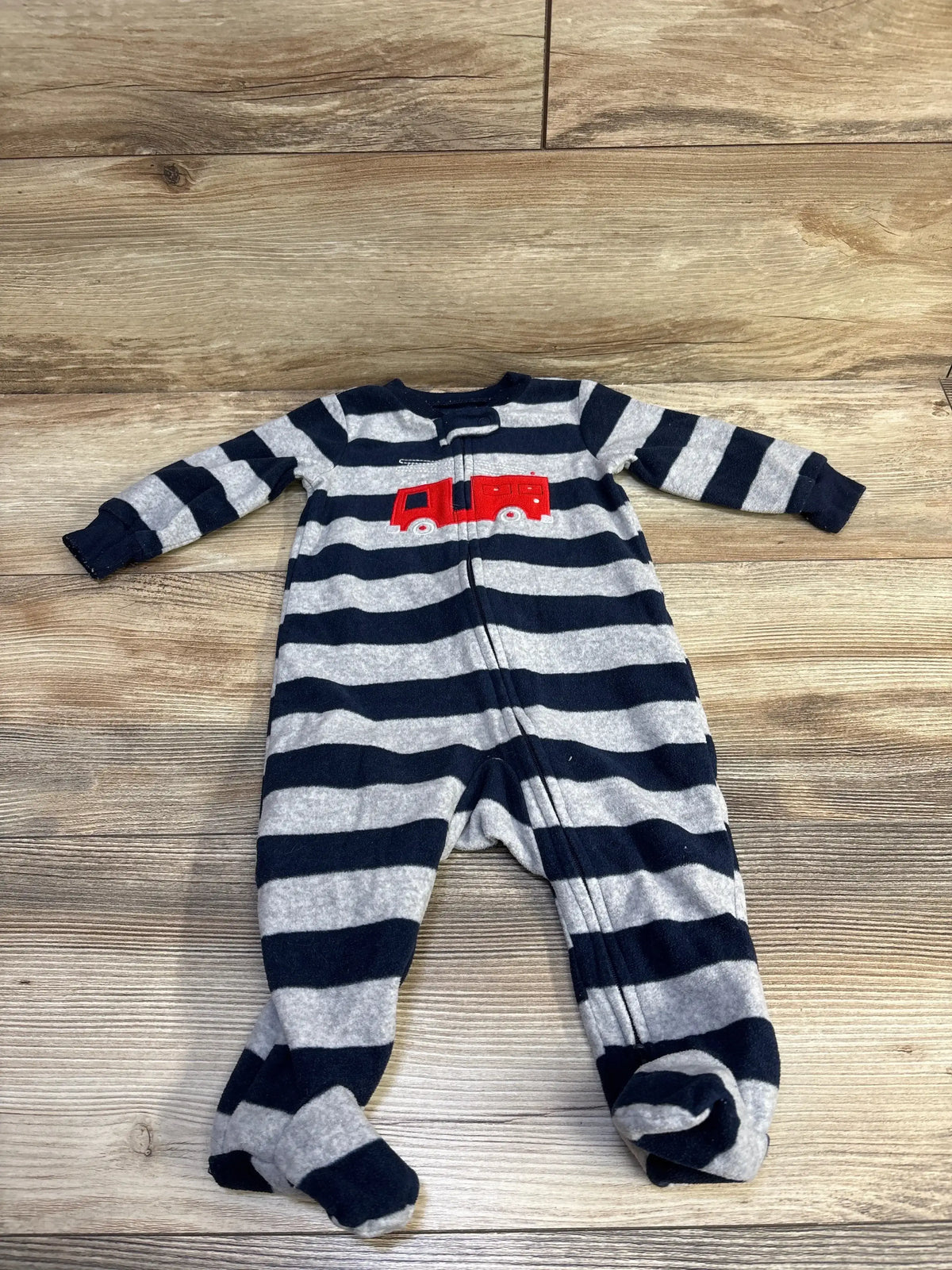 Front flat lay of Carter’s grey and navy striped footed blanket sleeper size 6m with zipper front and red fire truck applique on wood background