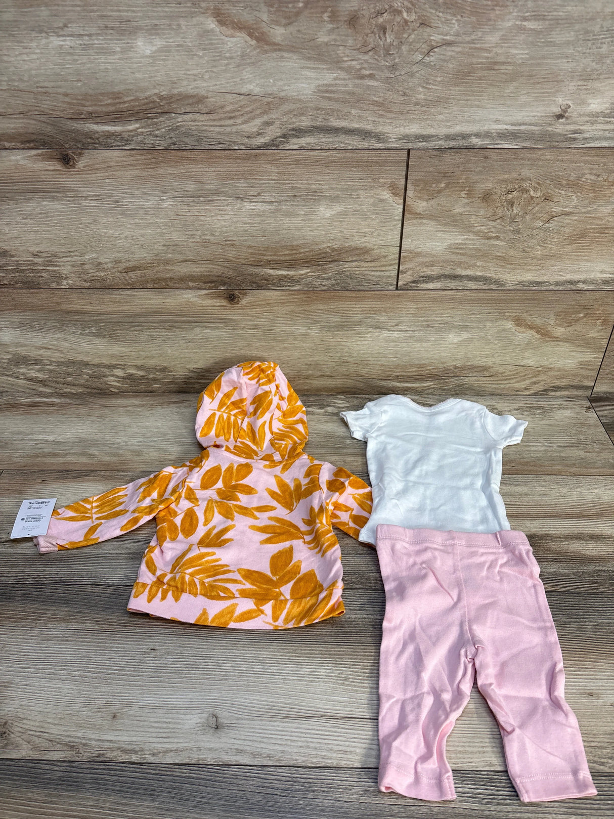 Baby girl outfit set with yellow leaf hoodie, white onesie, and pink leggings on wood floor