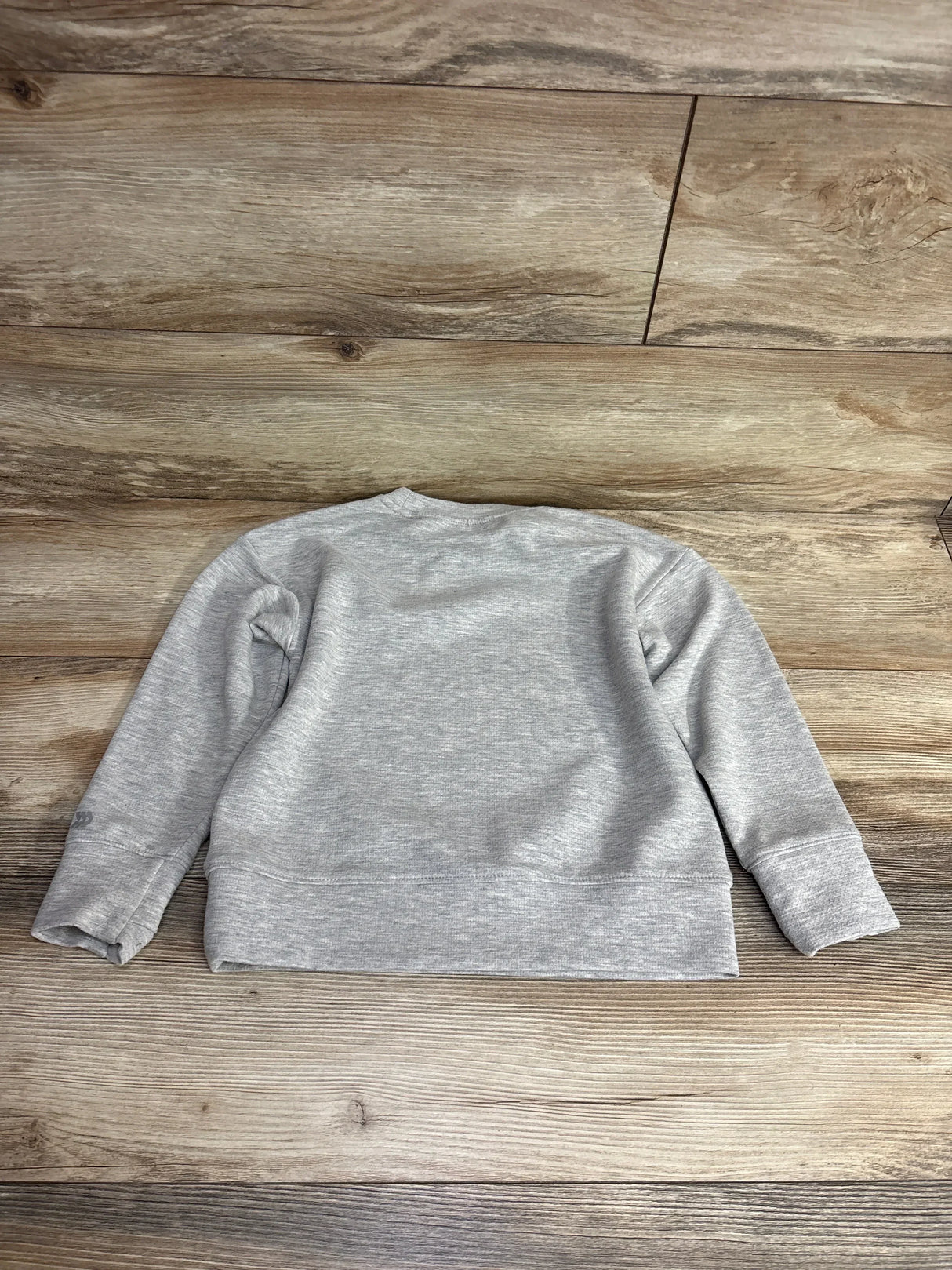 Gray kids long sleeve sweatshirt laid flat on wooden floor