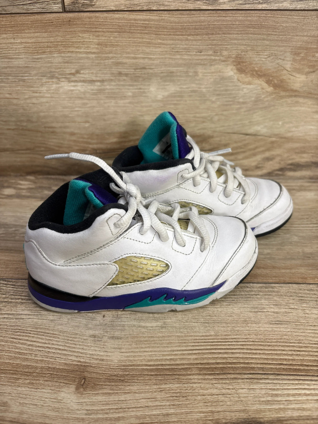 Side view of Air Jordan 5 Retro TD Grape sneakers size 10C, white leather with purple and teal midsole accents on wood