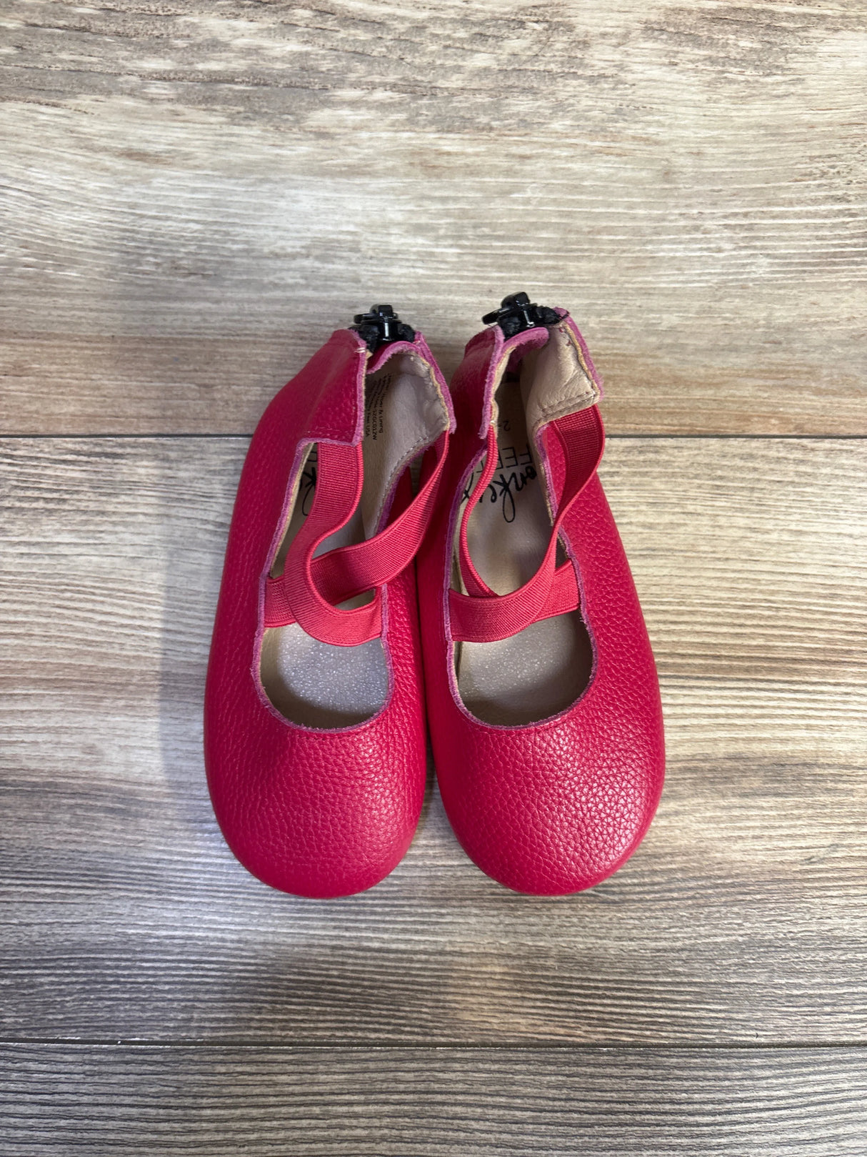 Top-down view of pink Monkey Feet Mary Jane toddler ballet flats size 7-8C showing criss-cross elastic straps and pebble-textured upper on wood floor