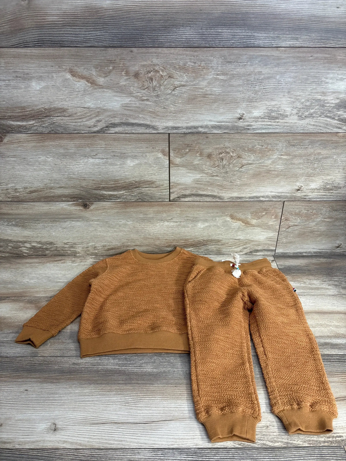 Flat lay of Sol Angeles oversized toddler sweater and jogger set size 2T showcasing textured knit and ribbed cuffs on wood plank background